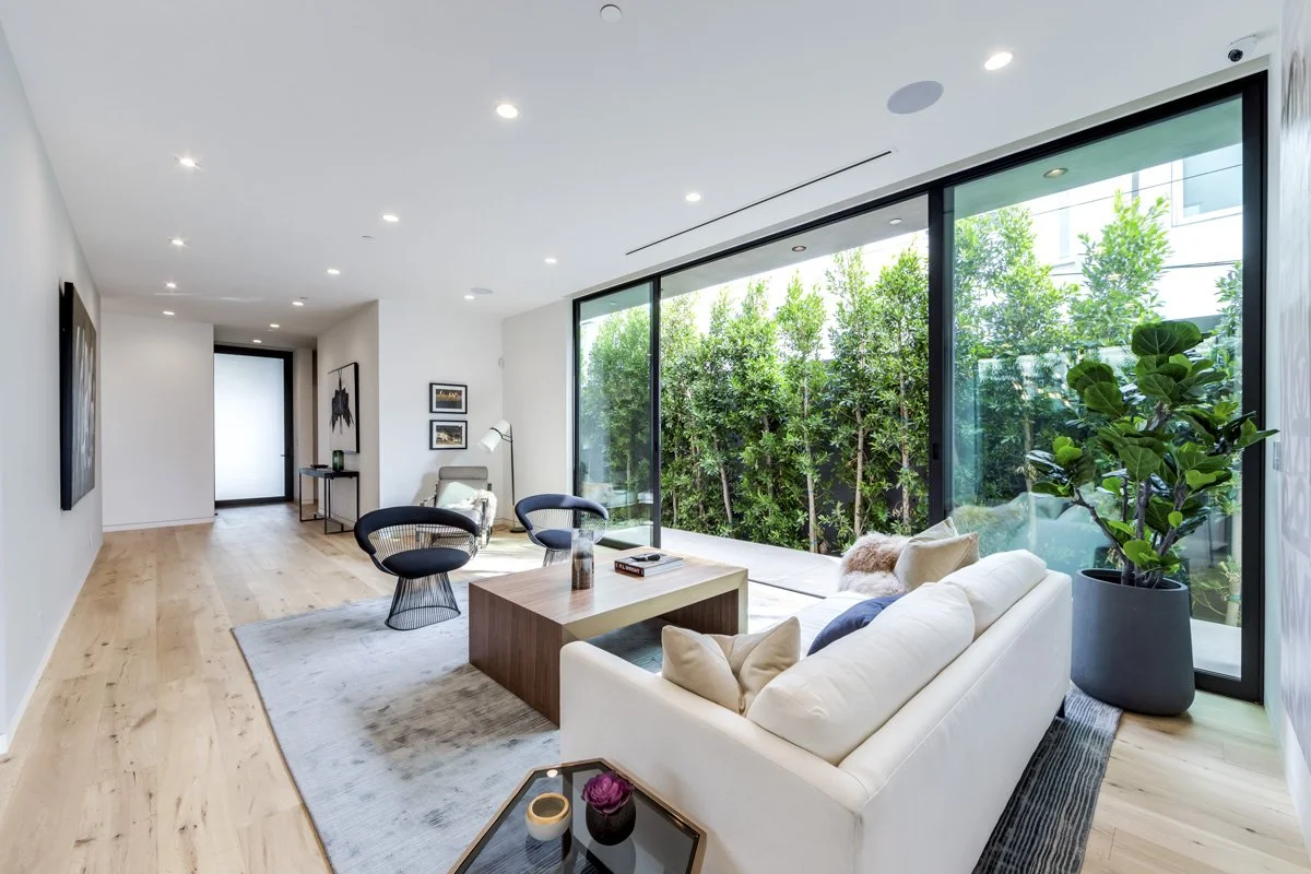 West Hollywood custom home living room with full-height sliding glass walls and garden courtyard view