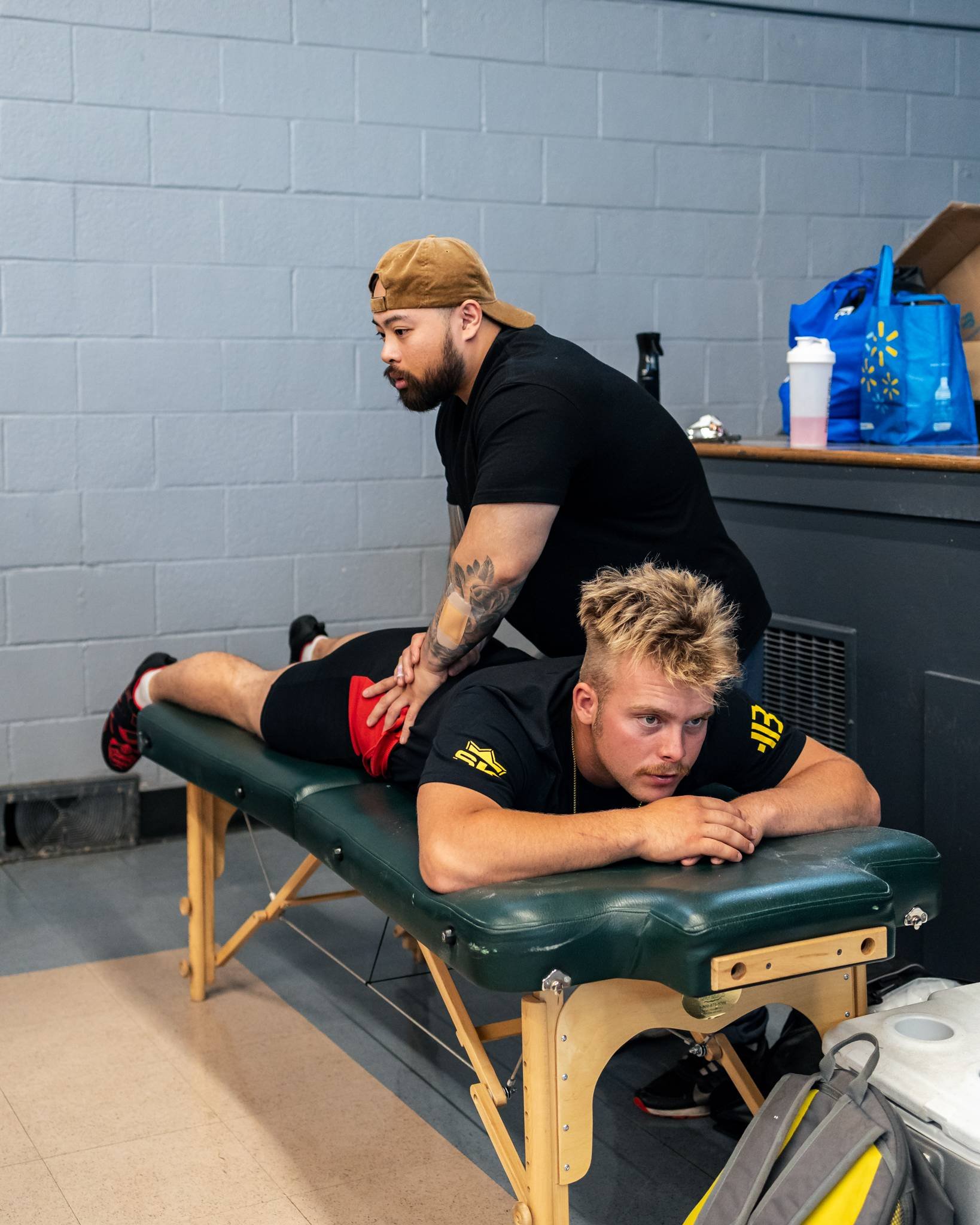 A man receives a back massage from a massage therapist in a clinic or gym setting.
