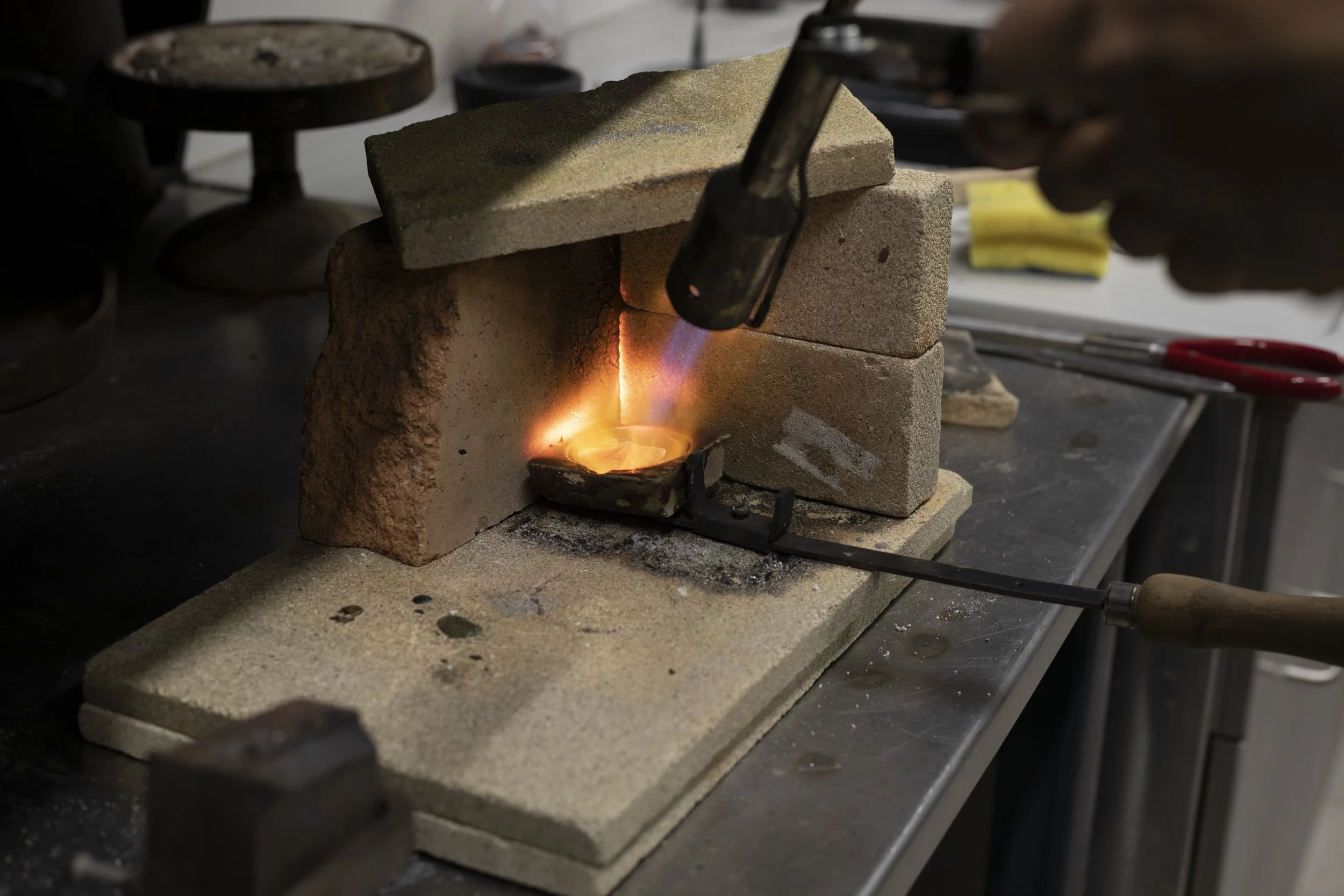 Traditional goldsmithing process of melting gold in a crucible, showcasing the transformation of metal for bespoke jewellery designs.