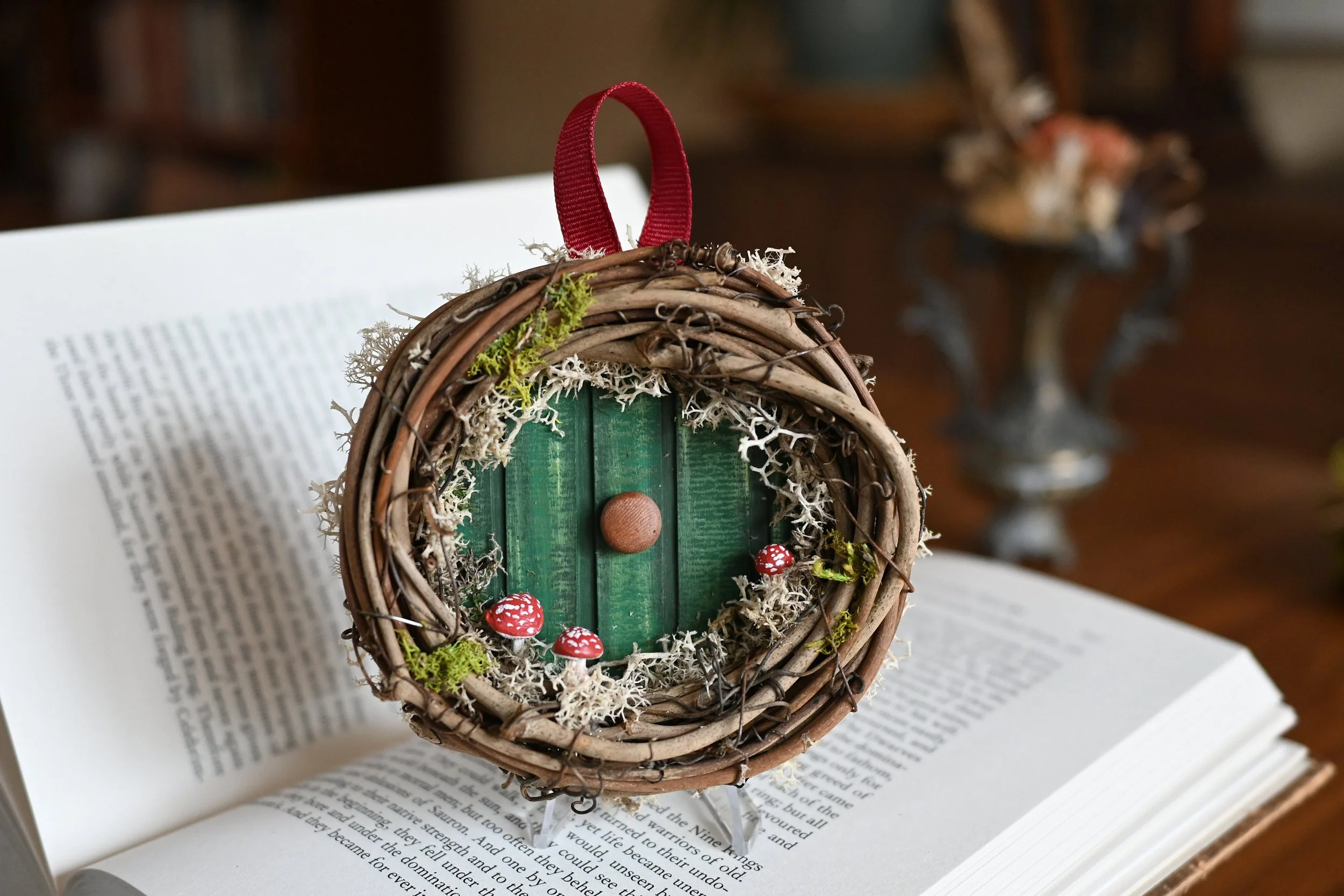 A small Hobbit door ornament made from a grapevine wreath, moss, hand-crafted clay mushrooms, and recycled materials for the door (SOLD)
