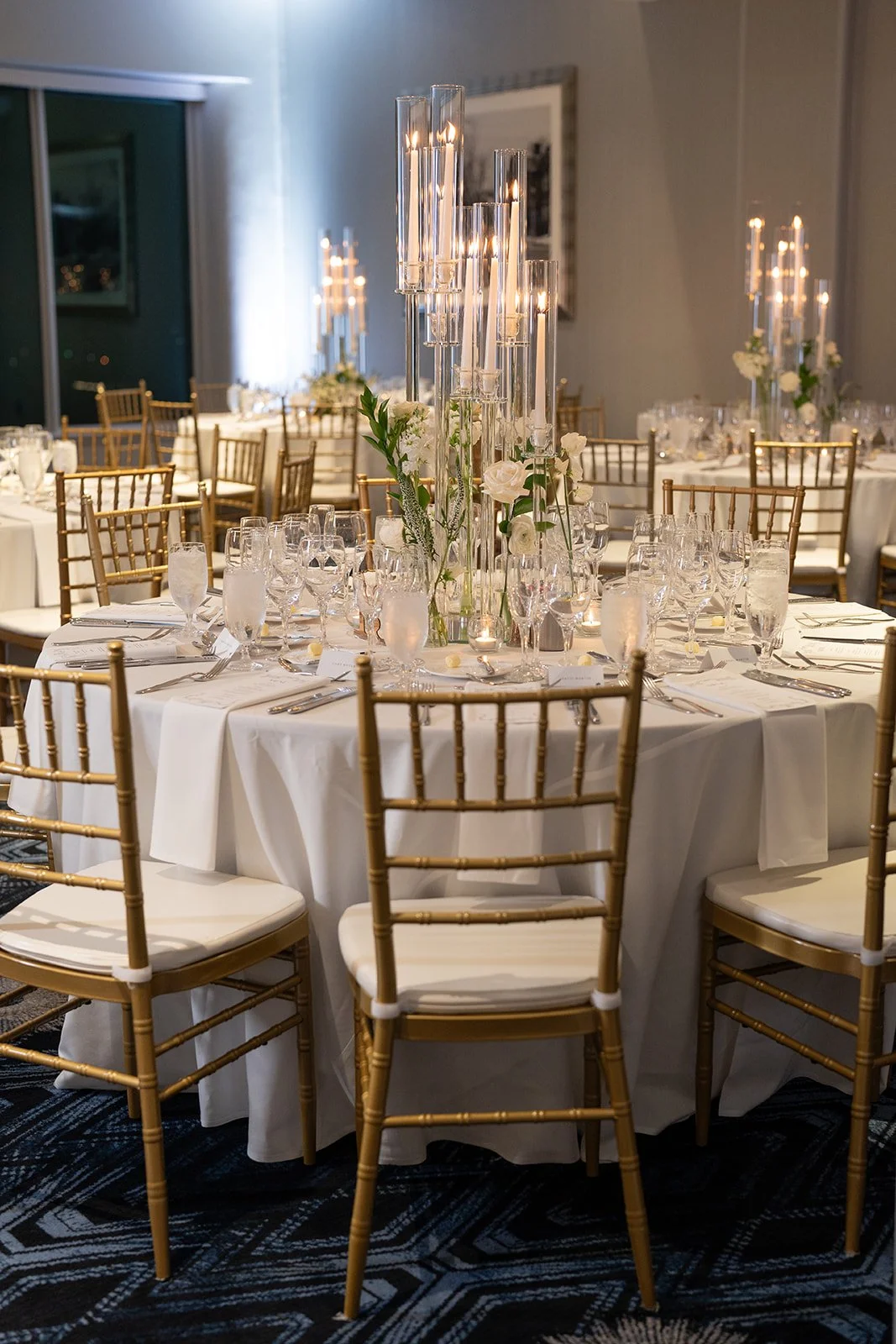 Chic and minimal: gold accents, crisp white linens, and the soft glow of candlelight set the scene.