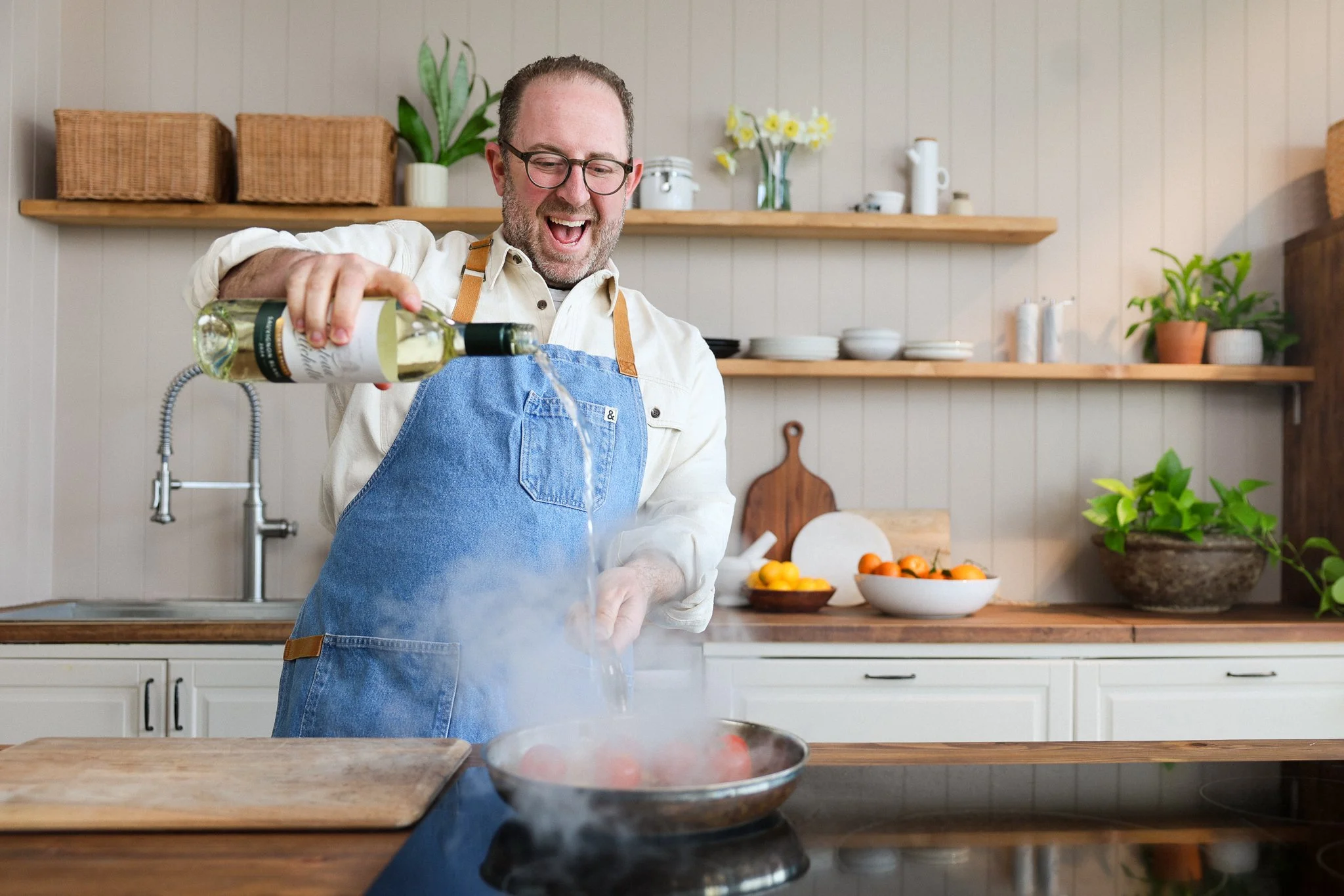 A man with glasses and a beard smiling outdoors, standing on a city sidewalk.