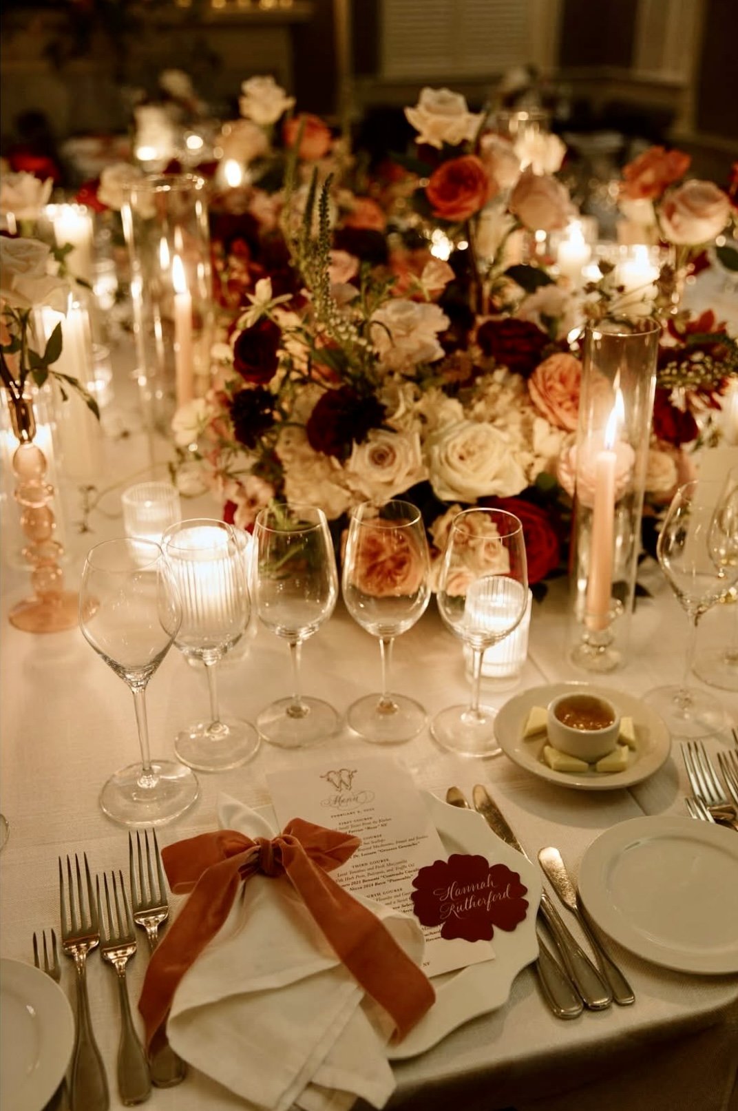 Elegant dinner table with floral centerpiece, candles, wine glasses, and place settings at a formal event.