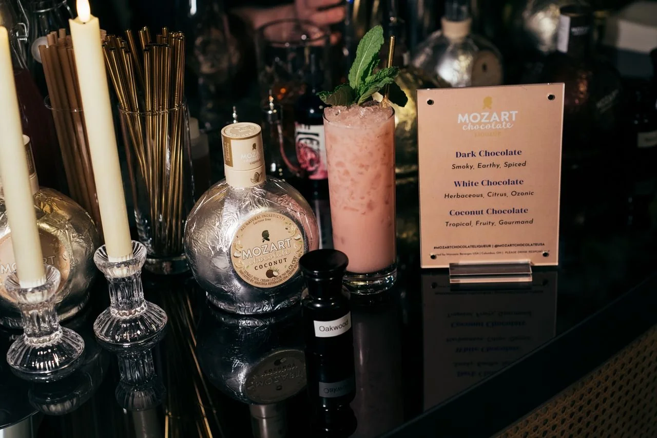 For Mozart Liqueur.

 Pineapple
 White Chocolate
 Pickled Cherry
 Lime
 Dark Rum
 Bourbon