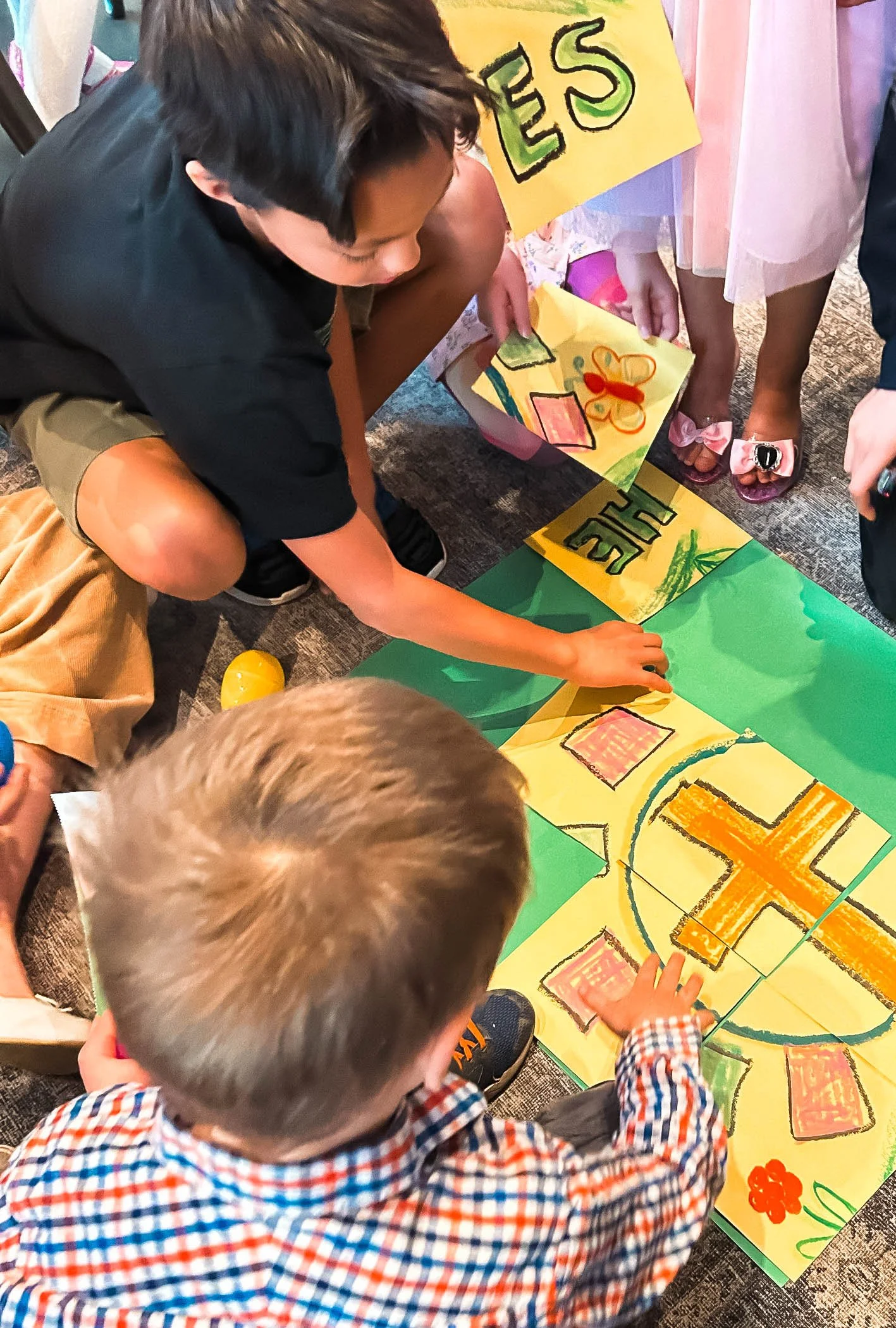 Children gathering around a colorful poster with drawings of a cross, hearts at Union Church in South Lake Union, Seattle.