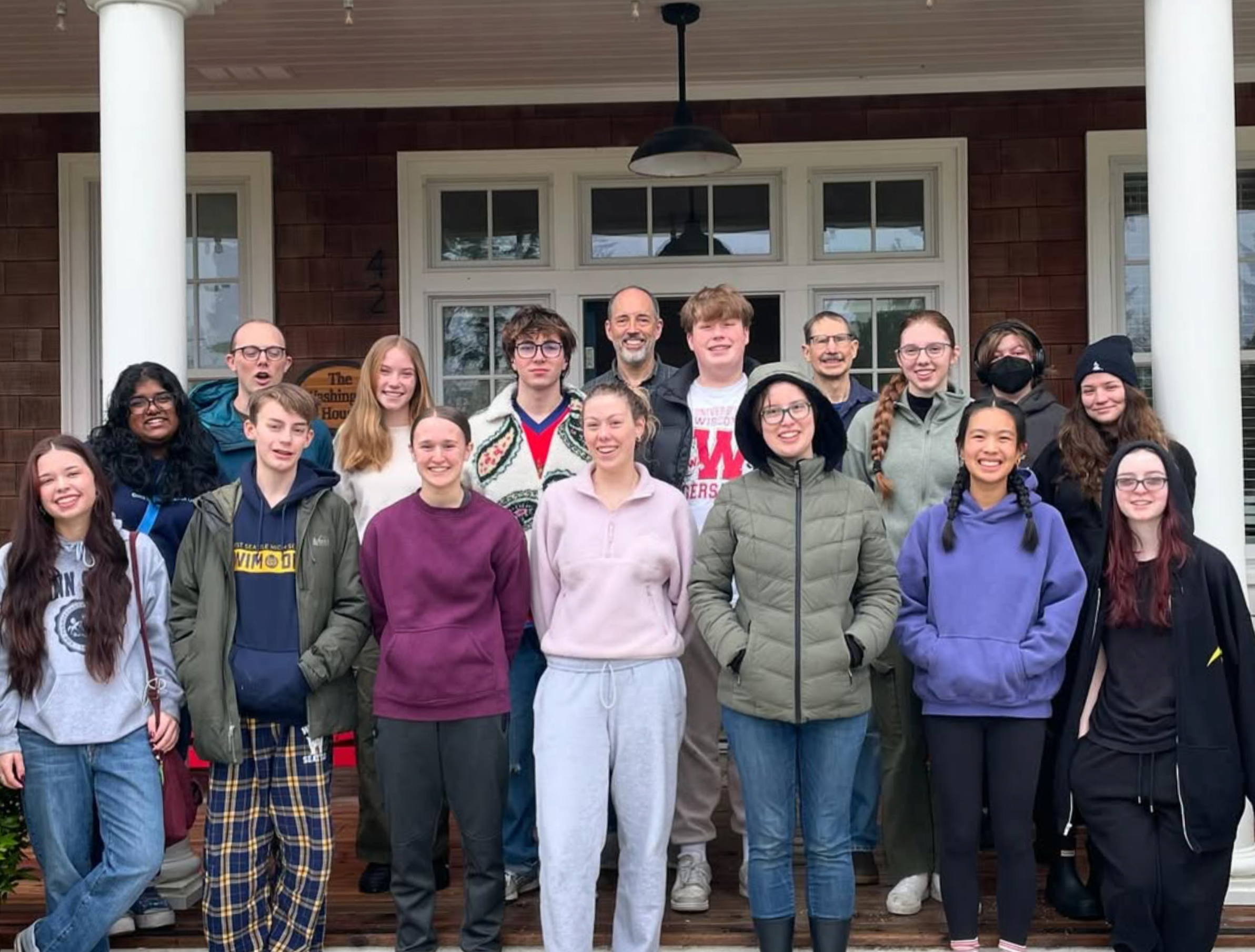 Union Youth Group Retreat with smiling teenagers and adults standing on front porch of a house with white columns and a dark brown exterior.