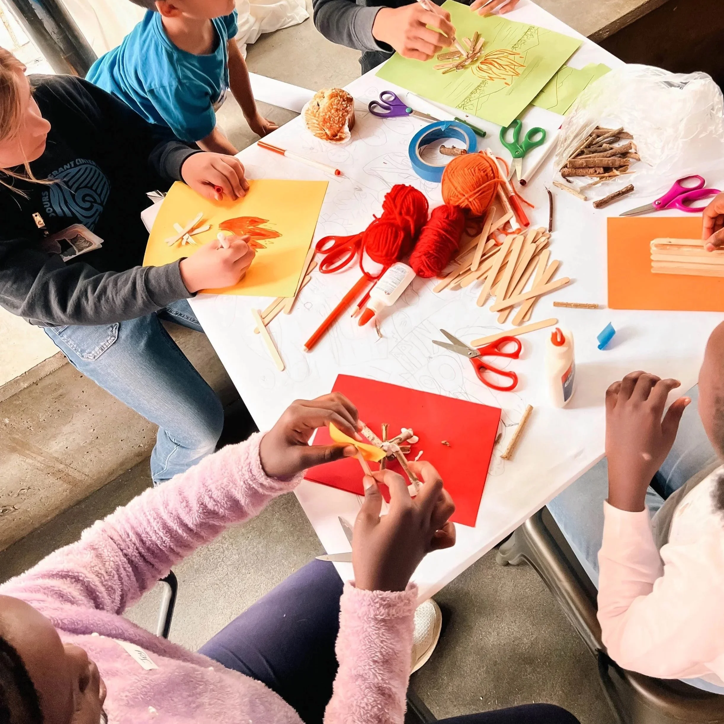 Children engaging in a crafting activity at a table with various art supplies including yarn, scissors, and popsicle sticks, creating colorful paper and 3D models at Union Church in South Lake Union, Seattle.