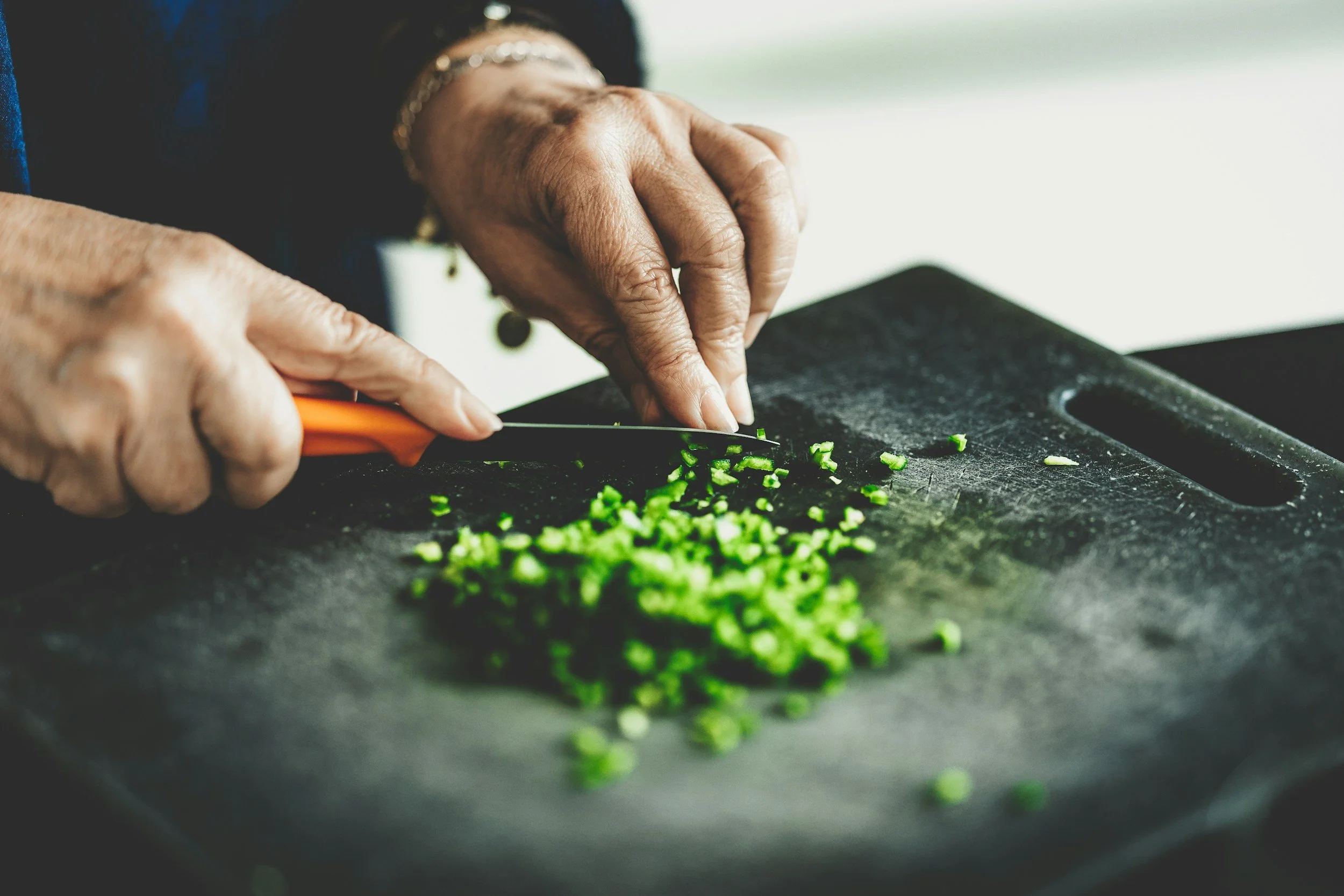 Hands chopping green onions on a cutting board at Union Church Seattle's Monday Chefs community meal program.