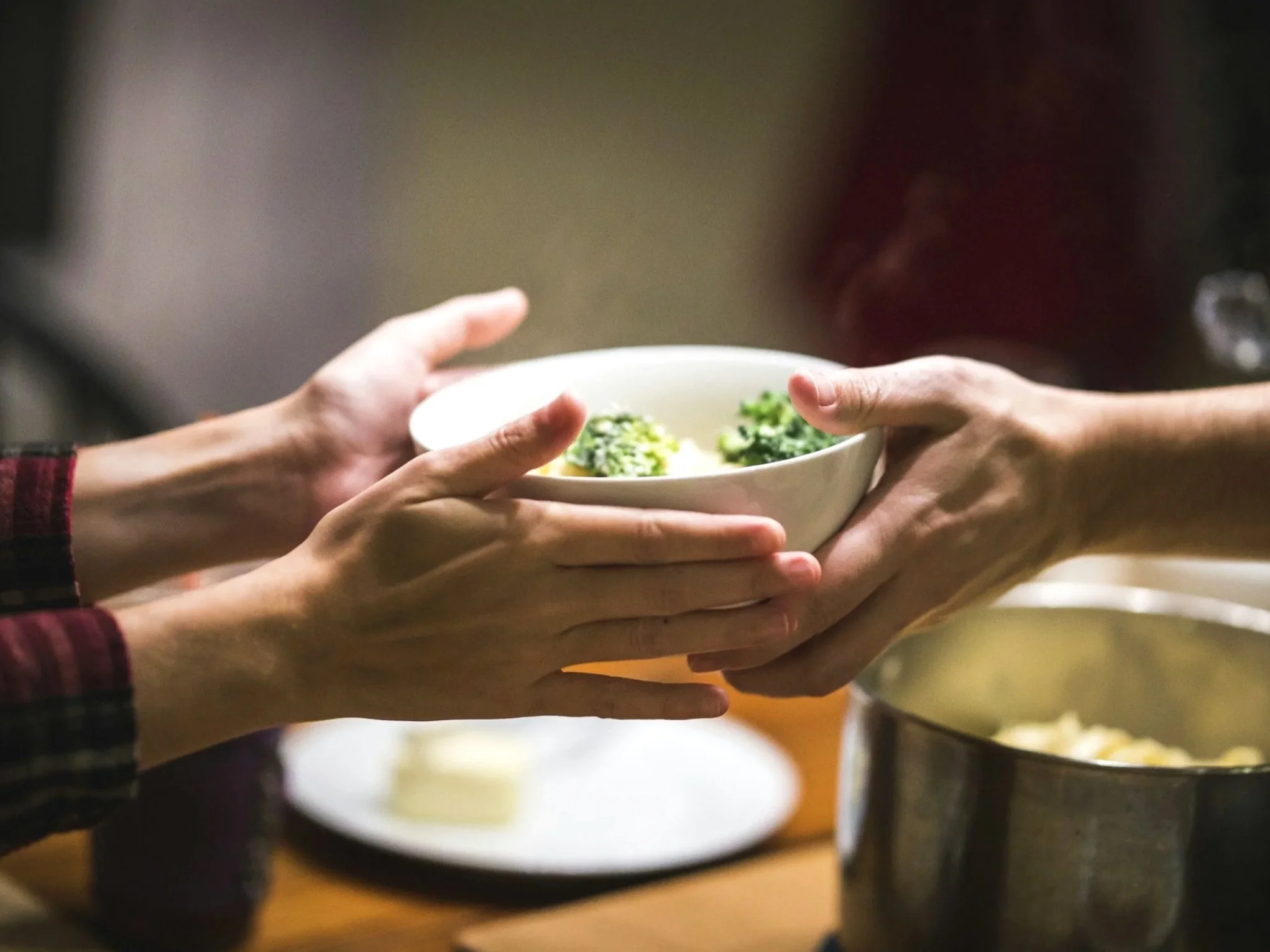 Hands passing a bowl of food — serving meals to women in transitional housing through Union Church Seattle's Supper Club