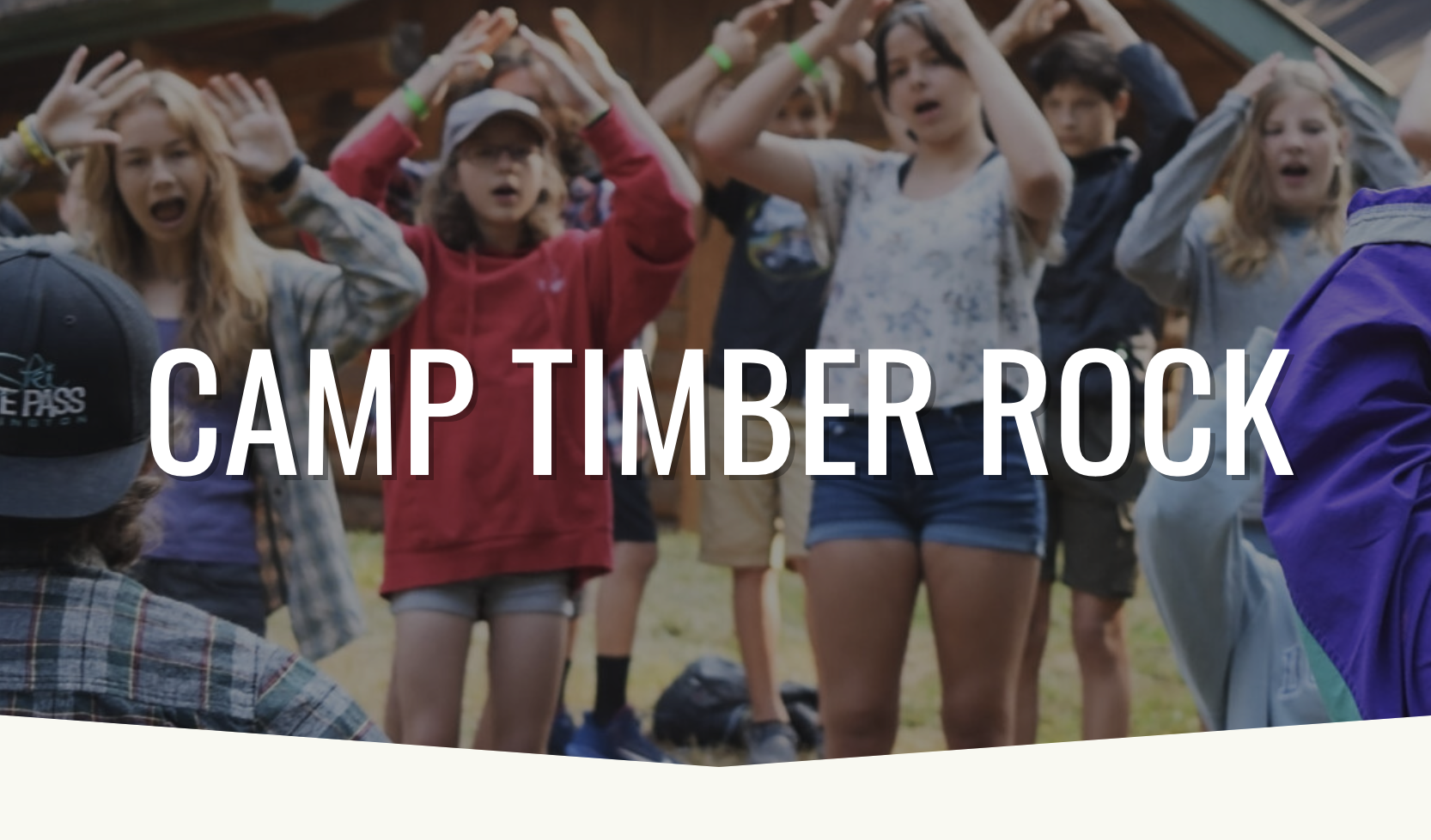 A group of youth singing with their hands raised up by their heads.