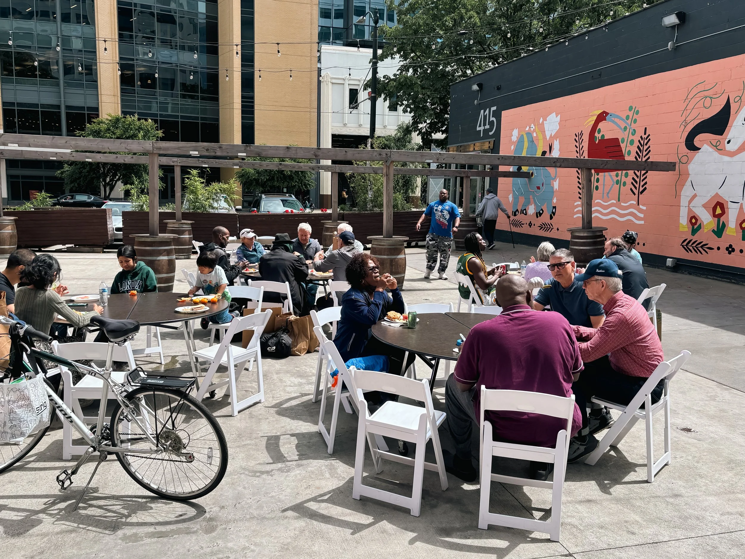 Four tables are set up outside, with people sitting around eating and talking on Memorial Day 2025.