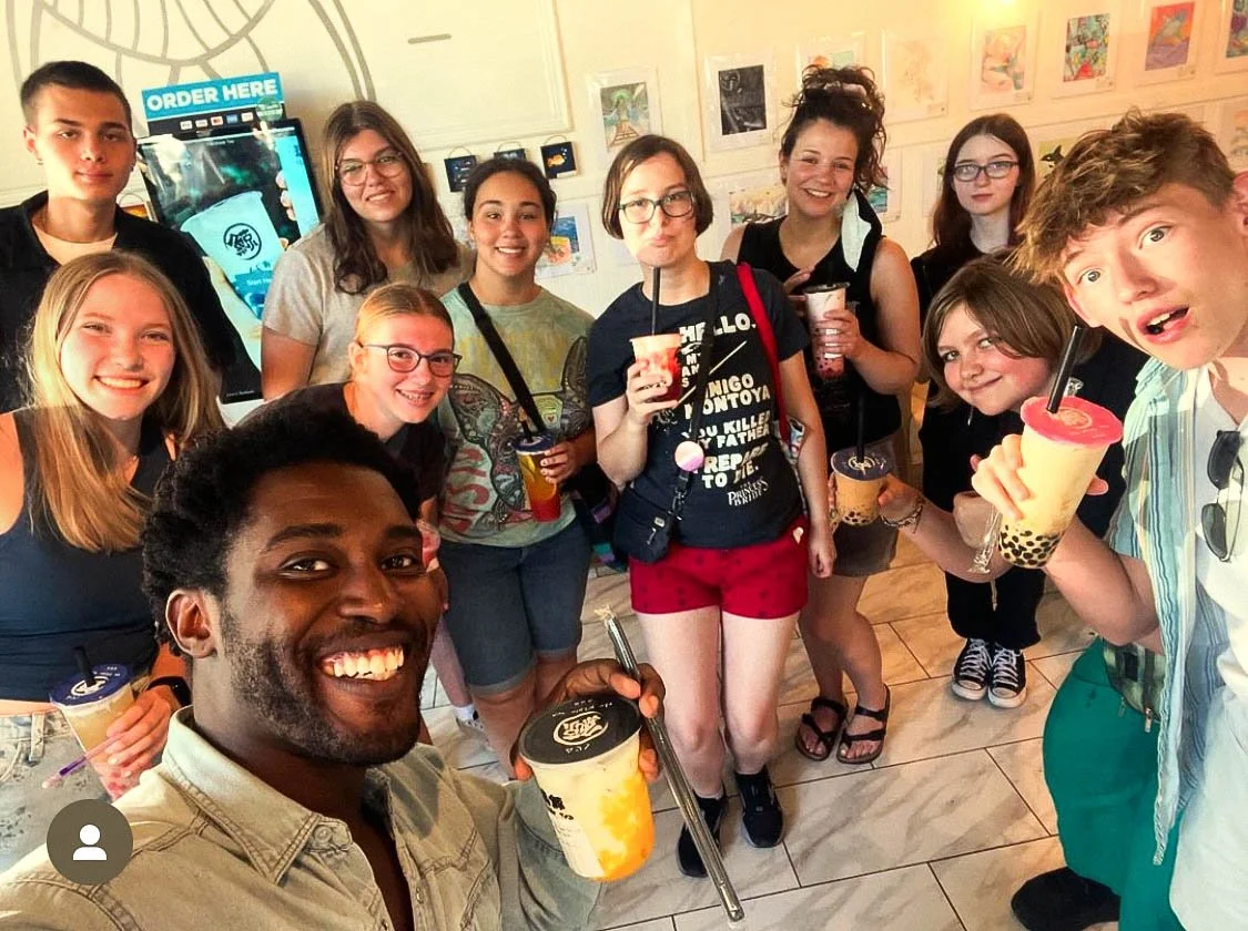 Union Youth Group event of young people and a man taking a selfie inside a bubble tea shop, holding bubble tea drinks and smiling at the camera.