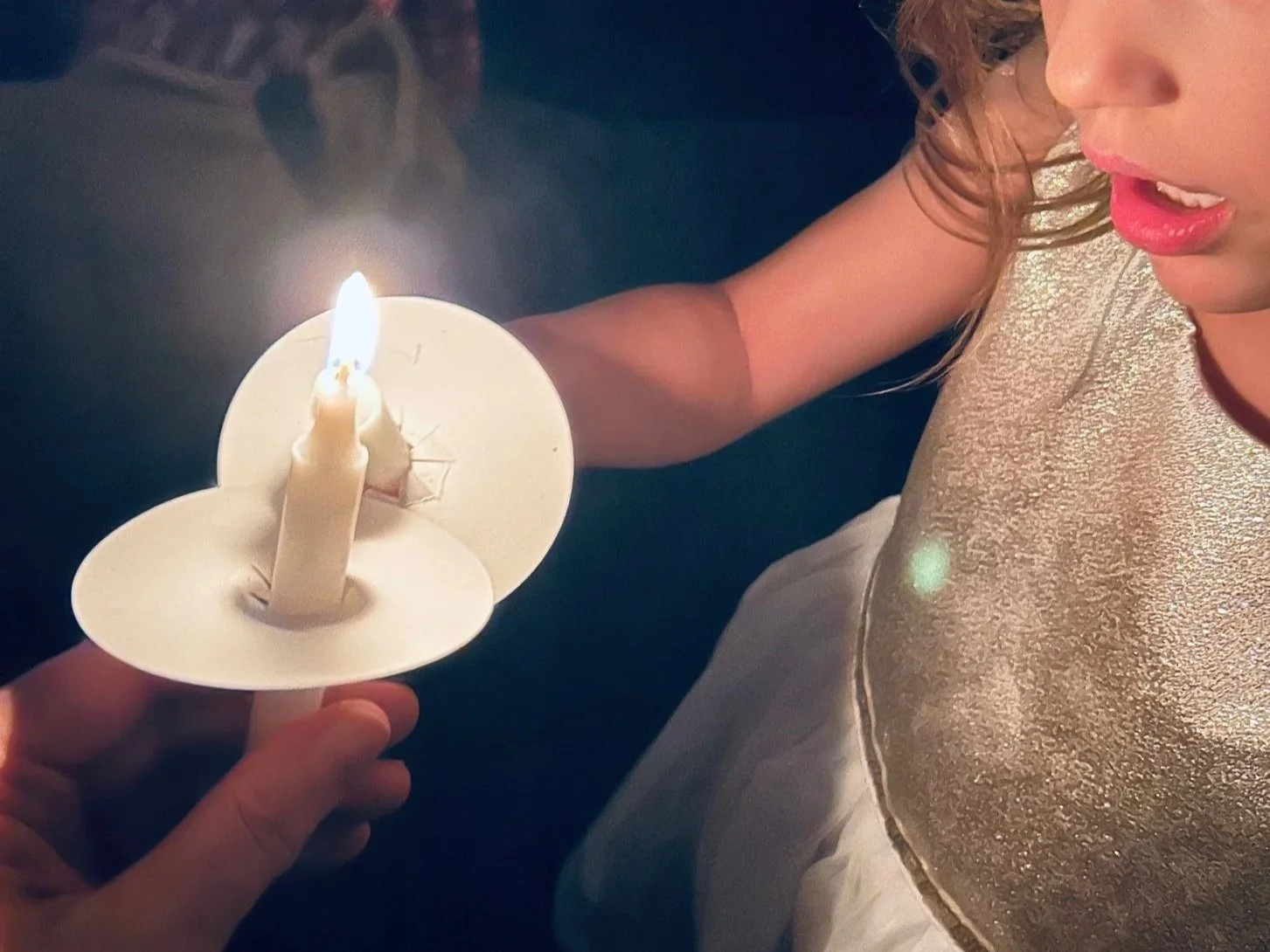 A girl in a shiny gold dress passing Christmas Eve light with candles at Union Church in South Lake Union, Seattle.