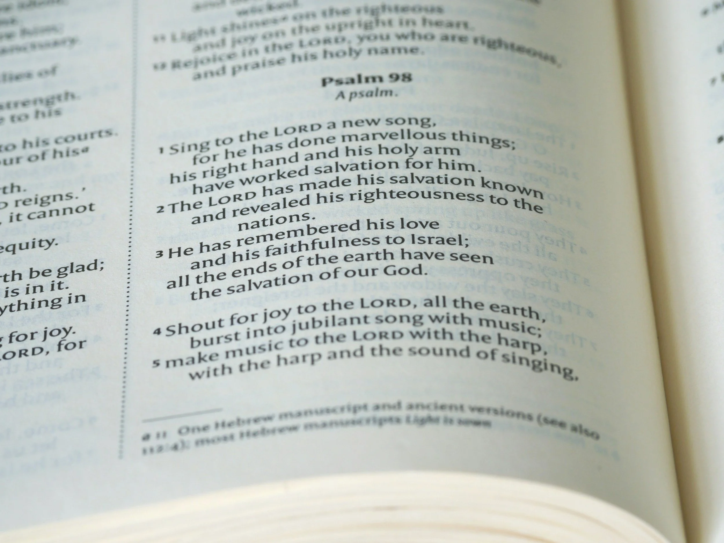 Open Bible page displaying Psalm 98, a hymn, with visible verses 1-5 about praising the Lord with music and joy.