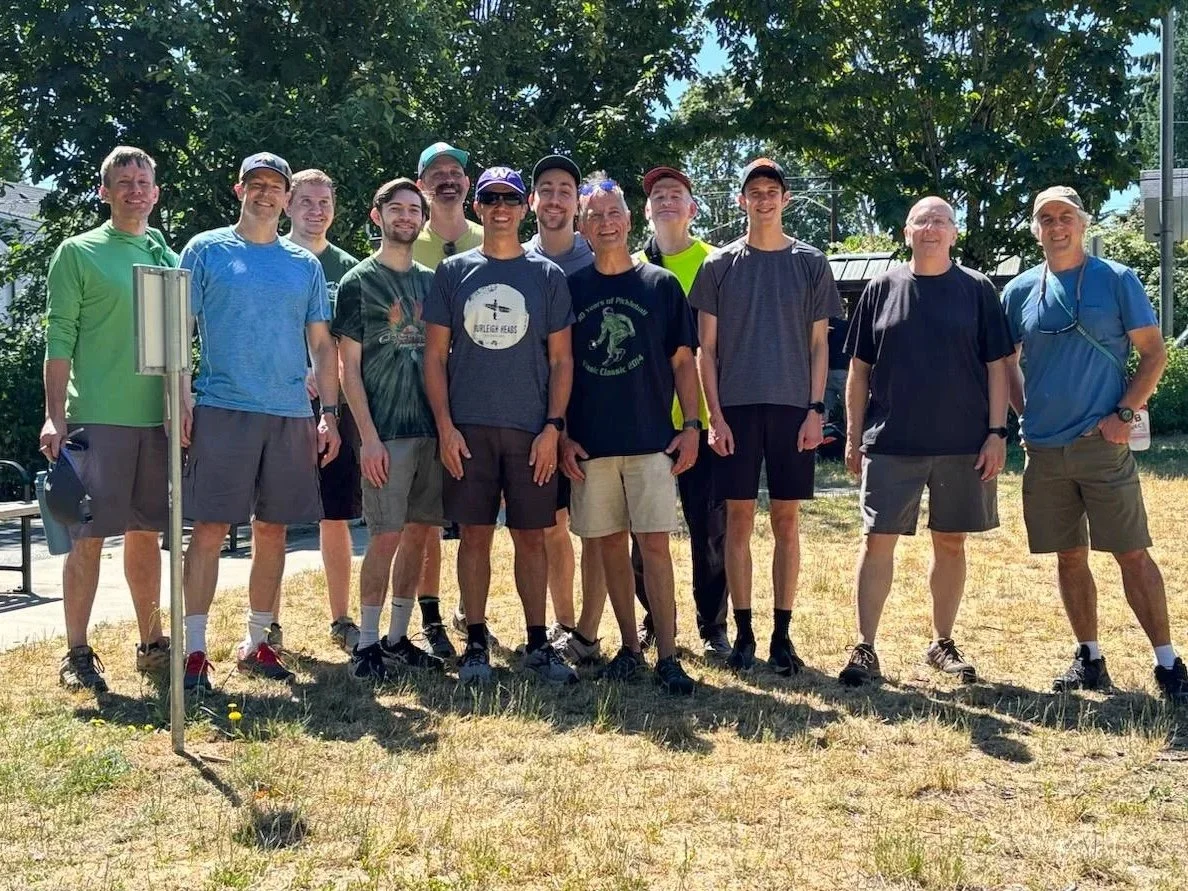 A group of men from Union Church stand together in a grassy field during the Men's Retreat