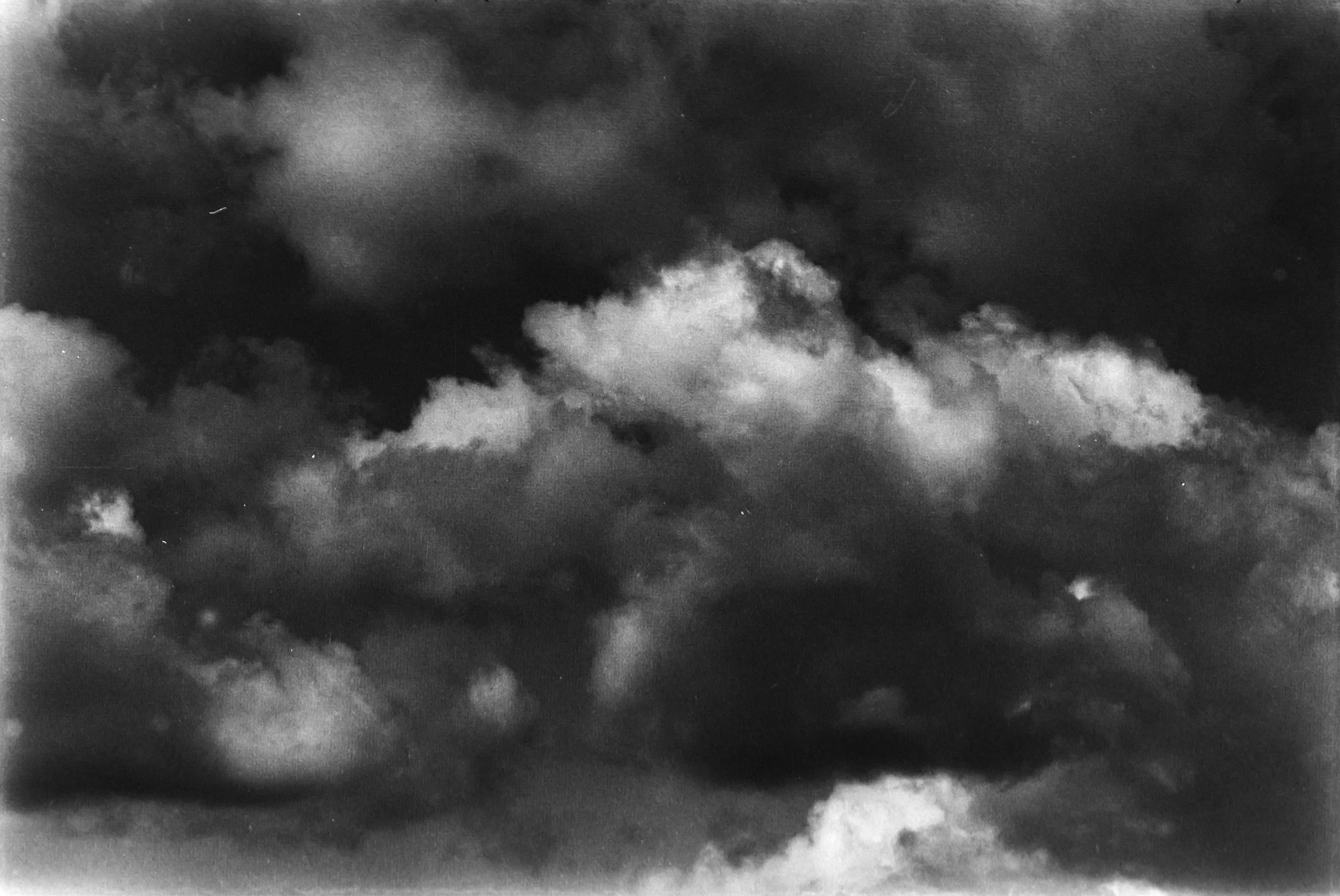 Black and white photo of a cloudy sky with dark and light clouds.
