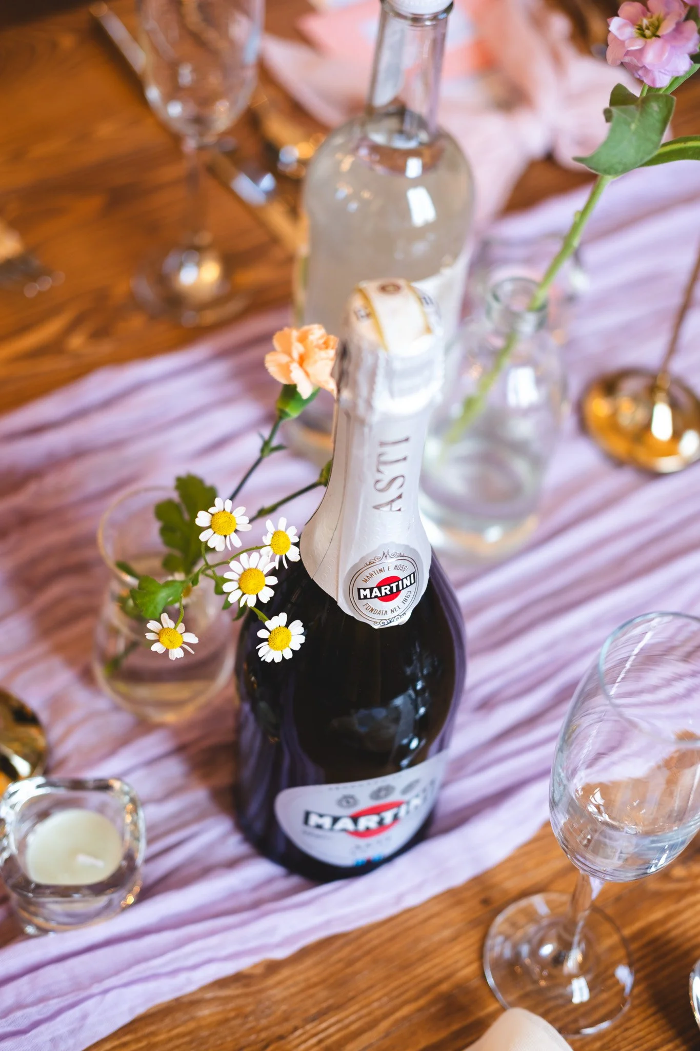 A bottle of Martini sparkling wine decorated with flowers on a dining table.