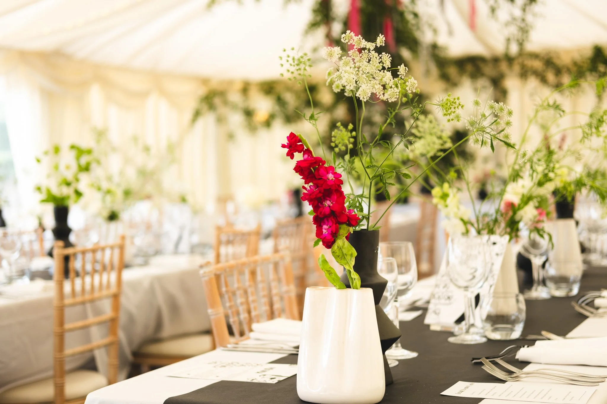 Table centerpiece with colorful flowers in vases at a decorated event venue.