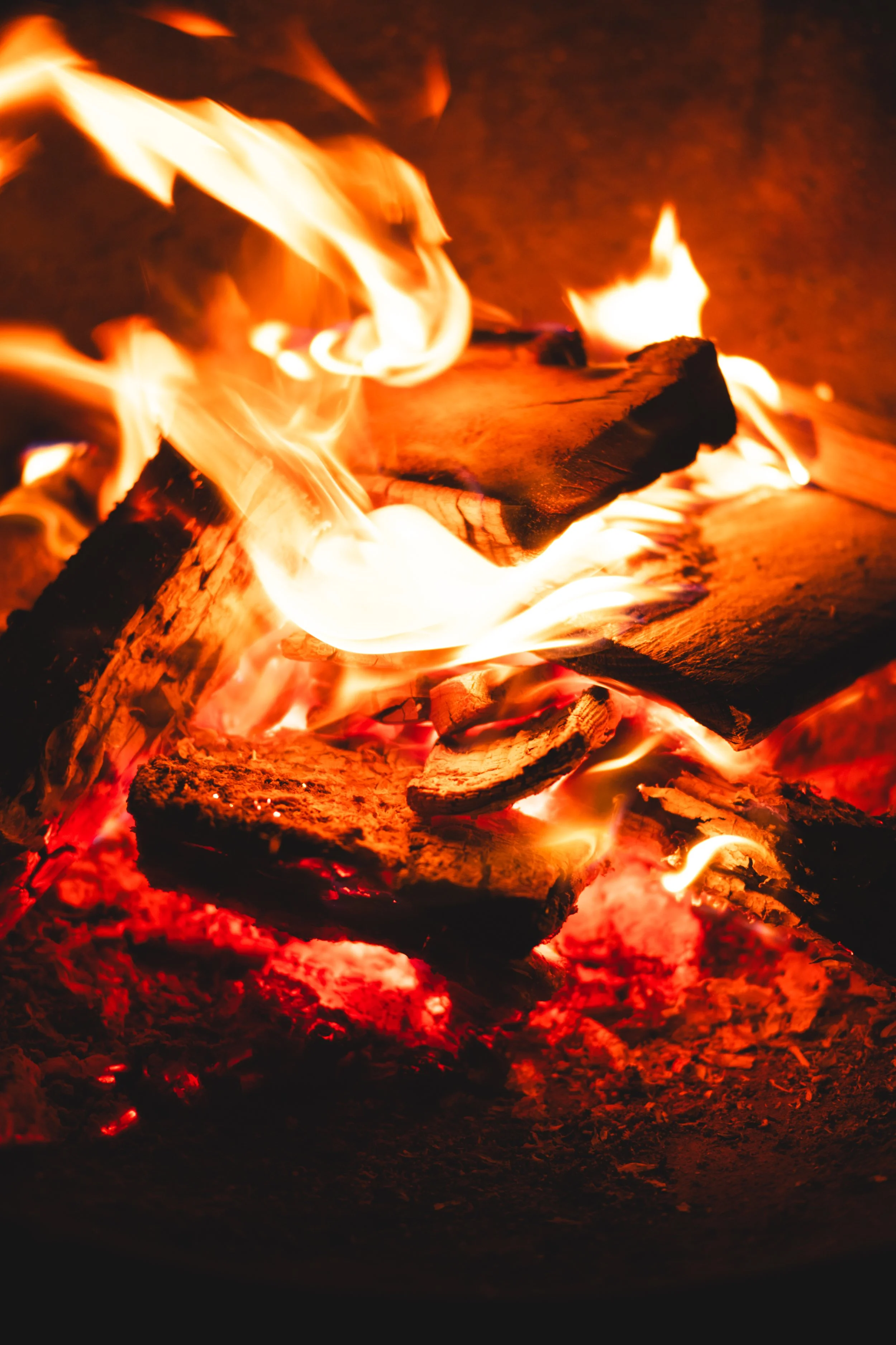 Wood burning in a fire with bright flames and glowing embers.