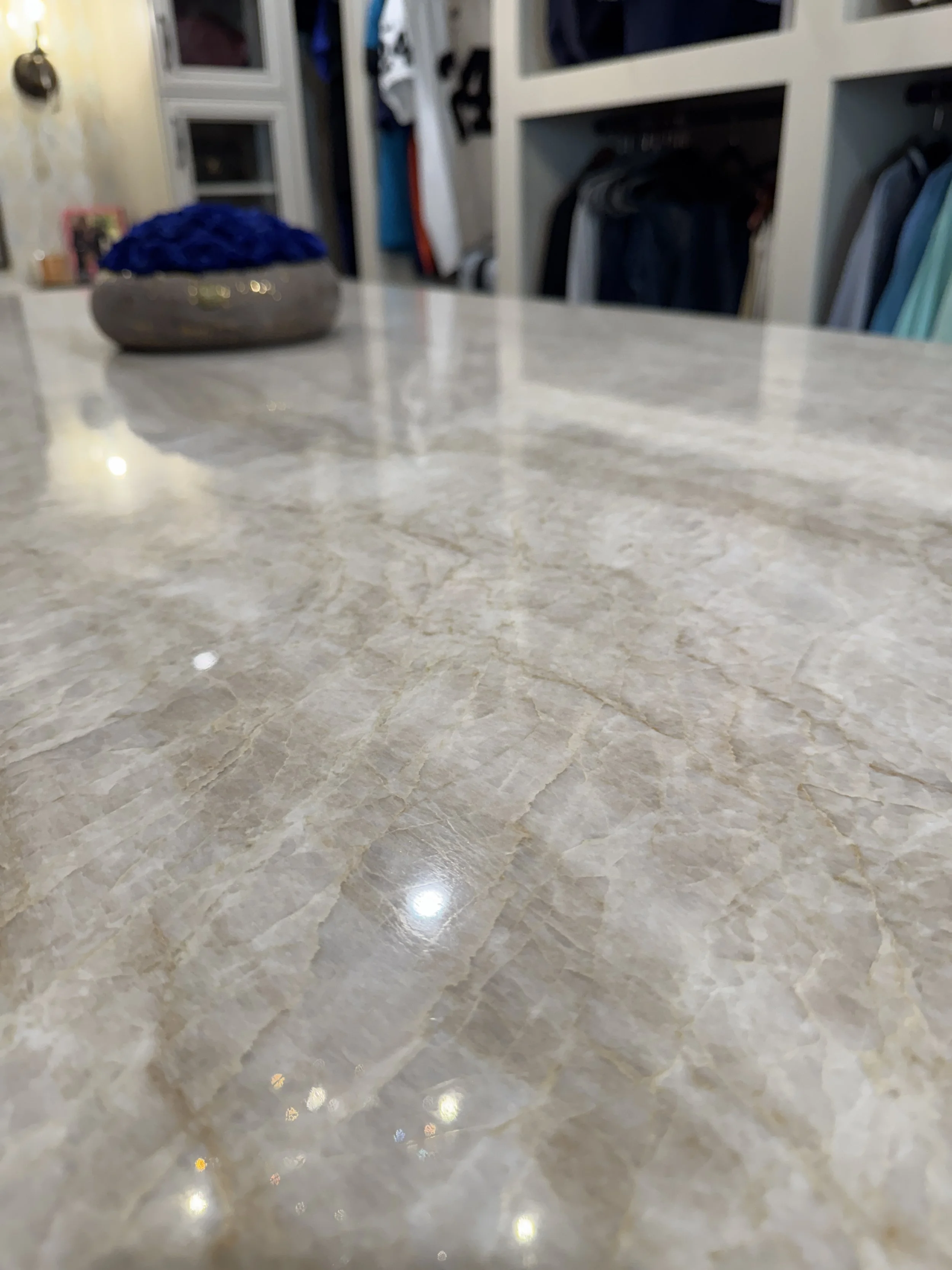 A beige marble tiled floor with a shiny surface, reflecting some light, and a decorative blue and gray bowl in the background.