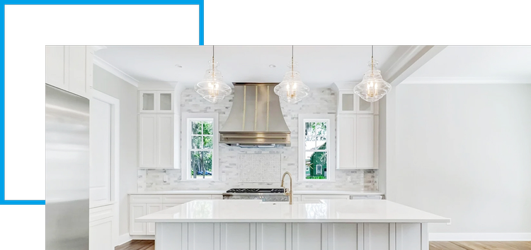 Modern kitchen with white cabinets, a large island, stainless steel appliances, a range hood, and three pendant lights hanging above the island.