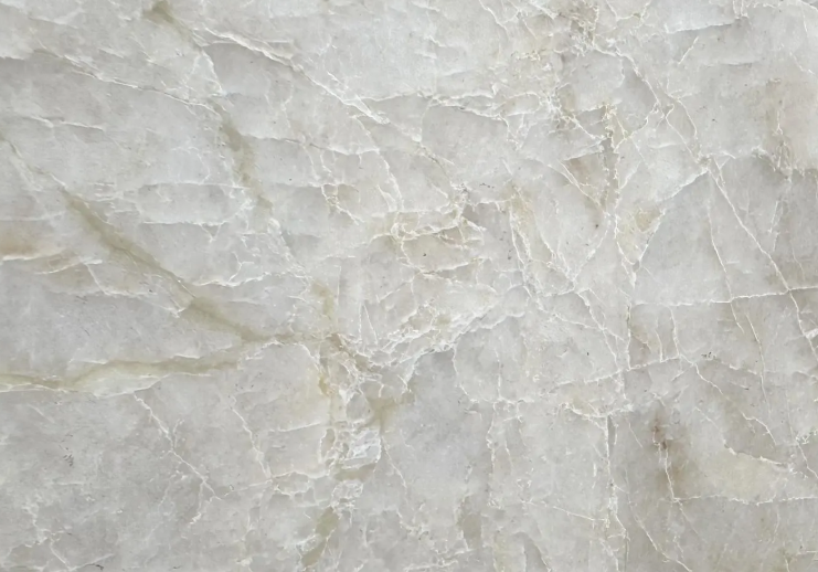 Close-up of a light-colored marble surface with natural veining and cracks.