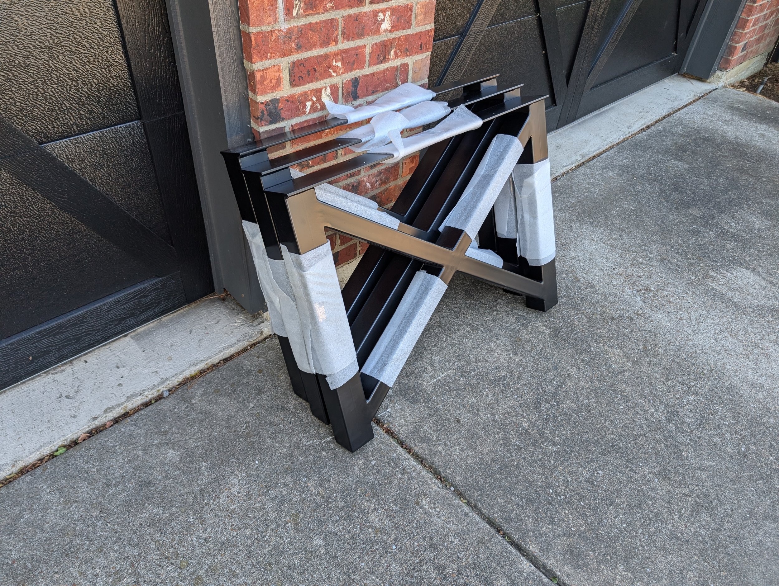 Custom powder-coated steel table legs with a modern geometric design, fabricated for strength, stability, and a clean industrial look to support solid wood table tops in custom furniture projects.