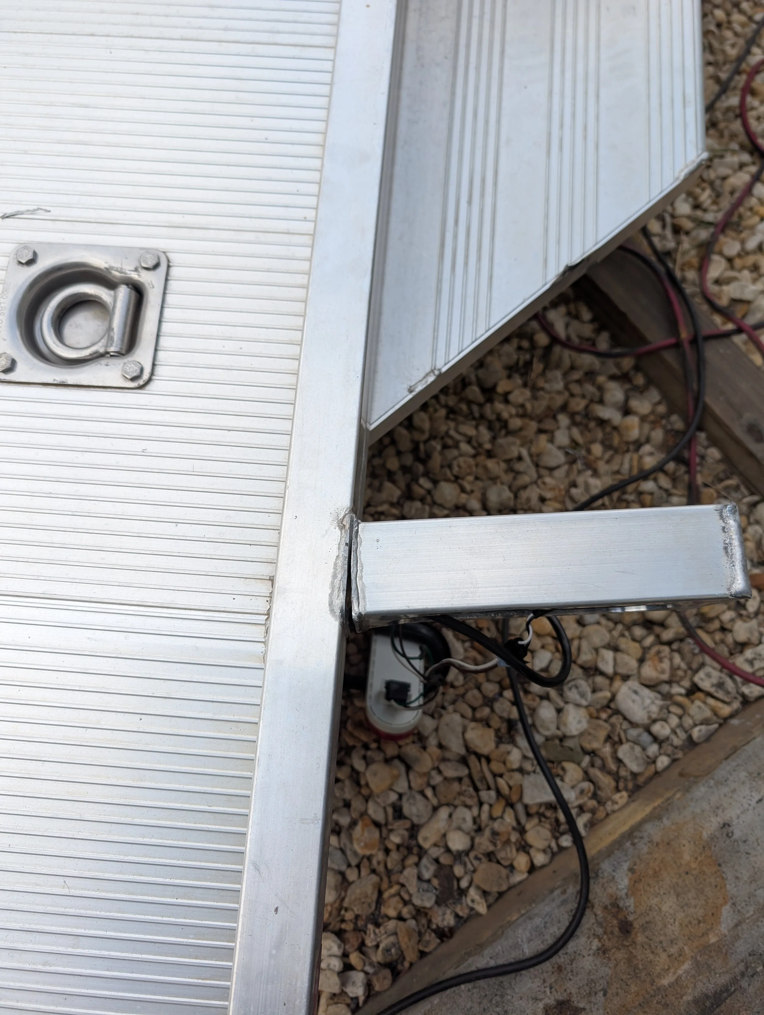 Aluminum trailer frame repair showing a reinforced support arm welded back into the trailer deck to restore structural strength and load support.