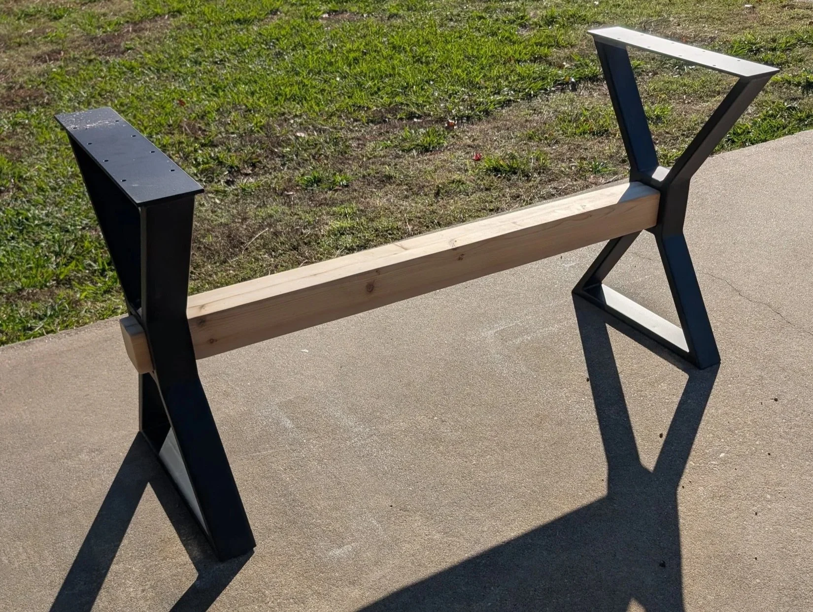 Custom steel table legs with a modern X-style design and solid wood stretcher, fabricated for strength, stability, and a bold industrial look to support solid wood table tops.