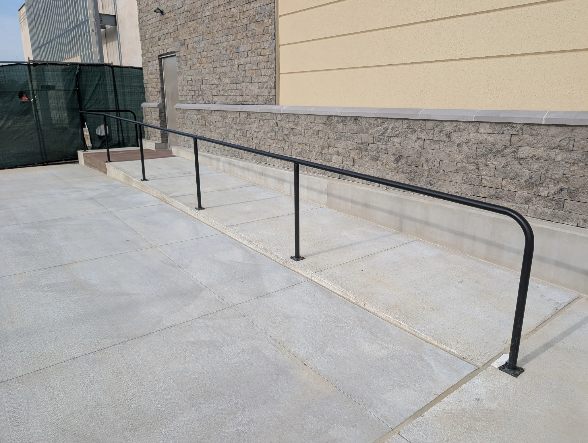 Custom fabricated black steel ADA handrail installed along a commercial walkway in Celina, Texas.