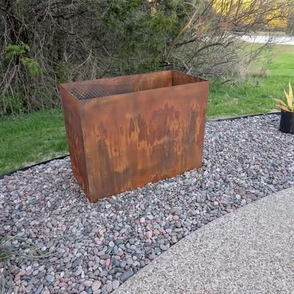 Custom welded steel planter with a natural rust finish for an outdoor landscaping project.