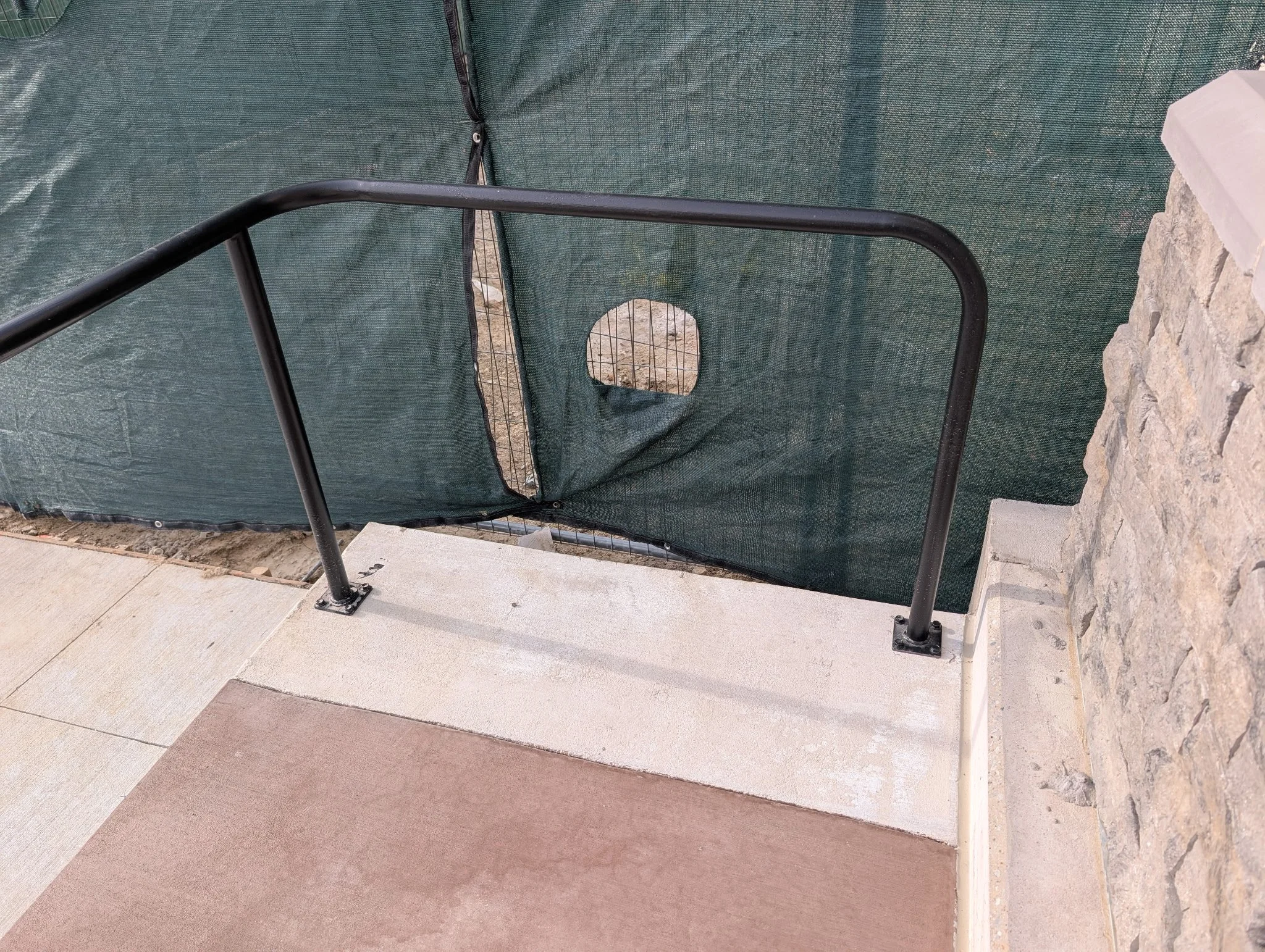 Custom black steel ADA handrail with rounded return installed at a commercial building in Celina, Texas.