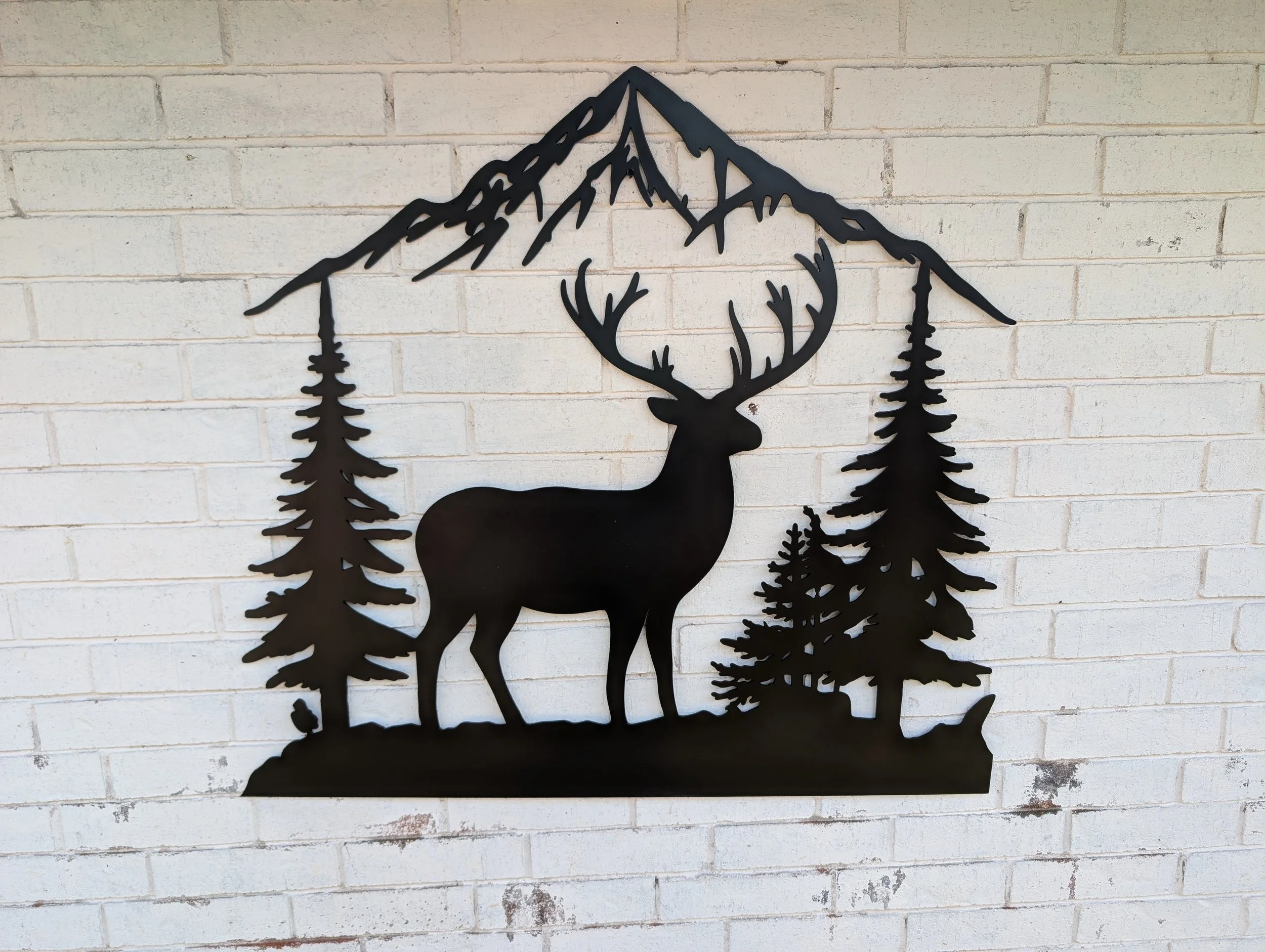 Custom CNC plasma cut steel deer and mountain wall art with pine trees.
