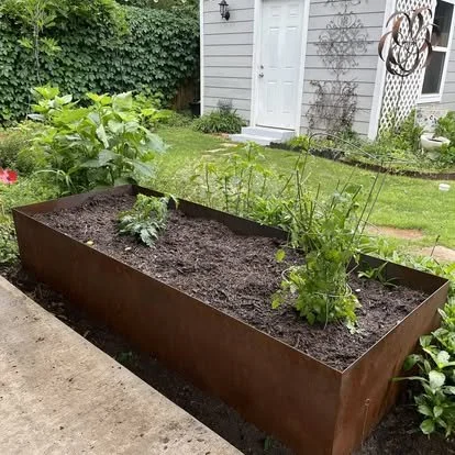 Custom steel planter installed beside a brick column with decorative stone and plants.