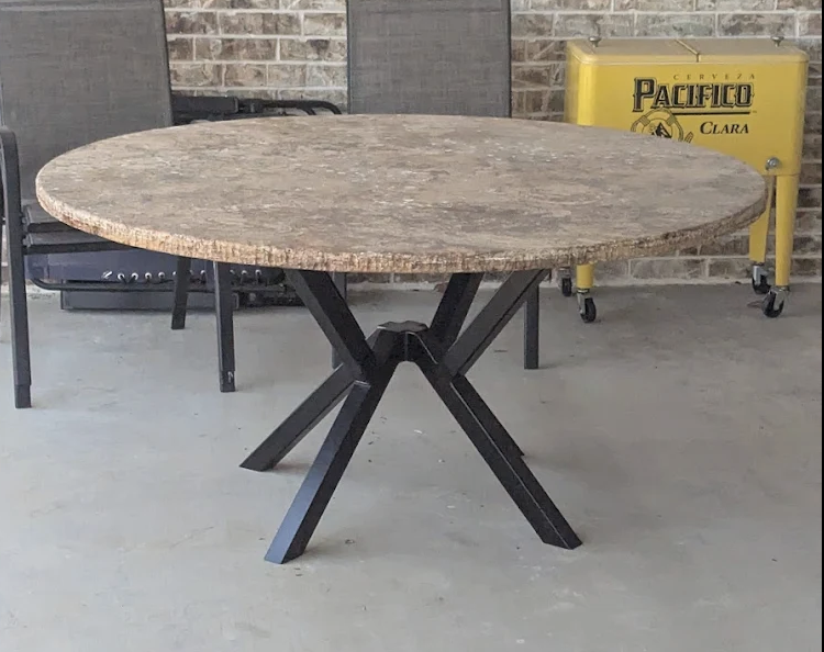 A custom round table featuring a solid stone top supported by a precision-fabricated steel pedestal base. The powder-coated steel base provides excellent stability while complementing the natural stone surface, making this table ideal for outdoor pat