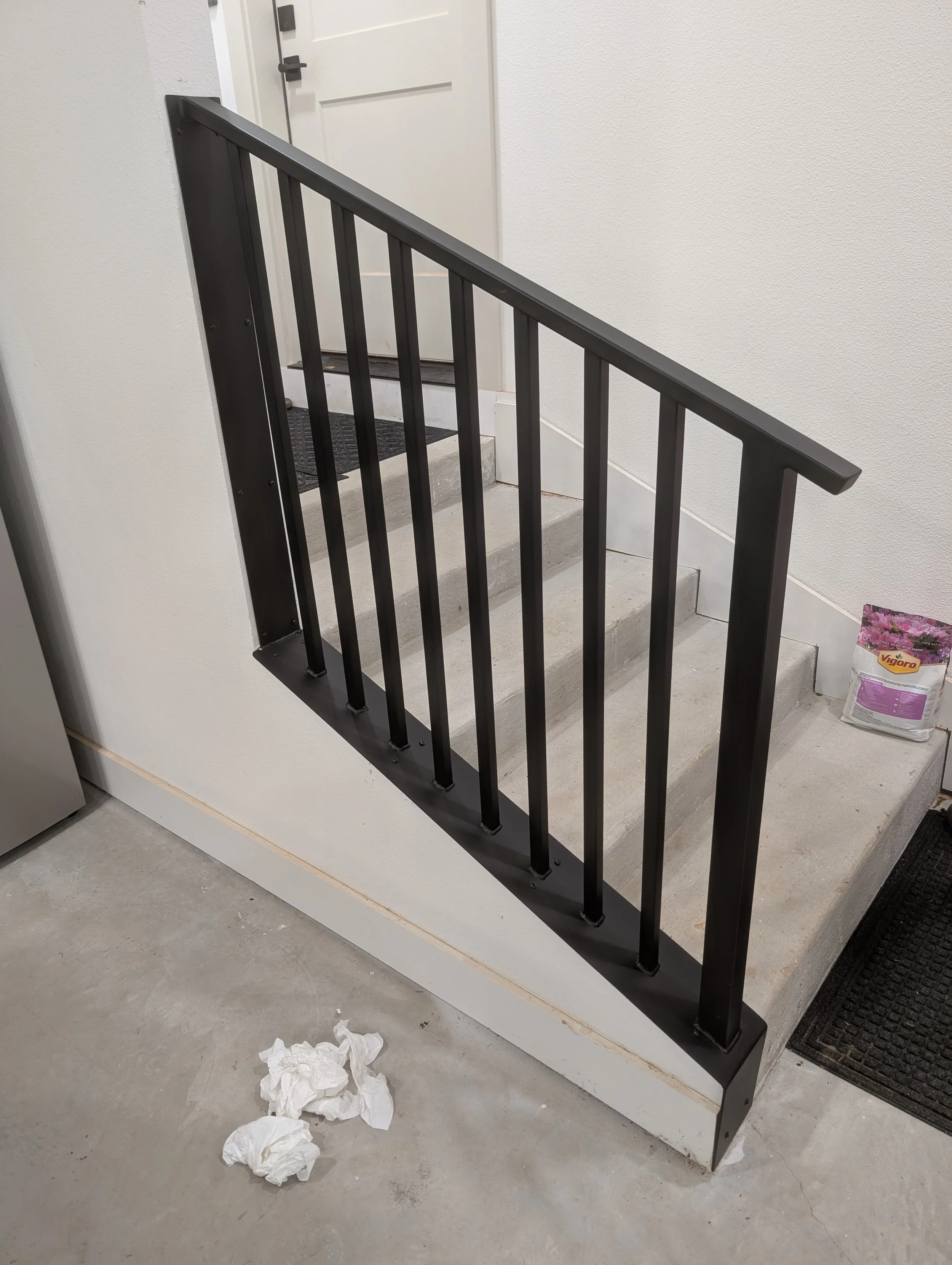 Custom black steel stair railing with vertical pickets fabricated and installed by JH Tig Works LLC.