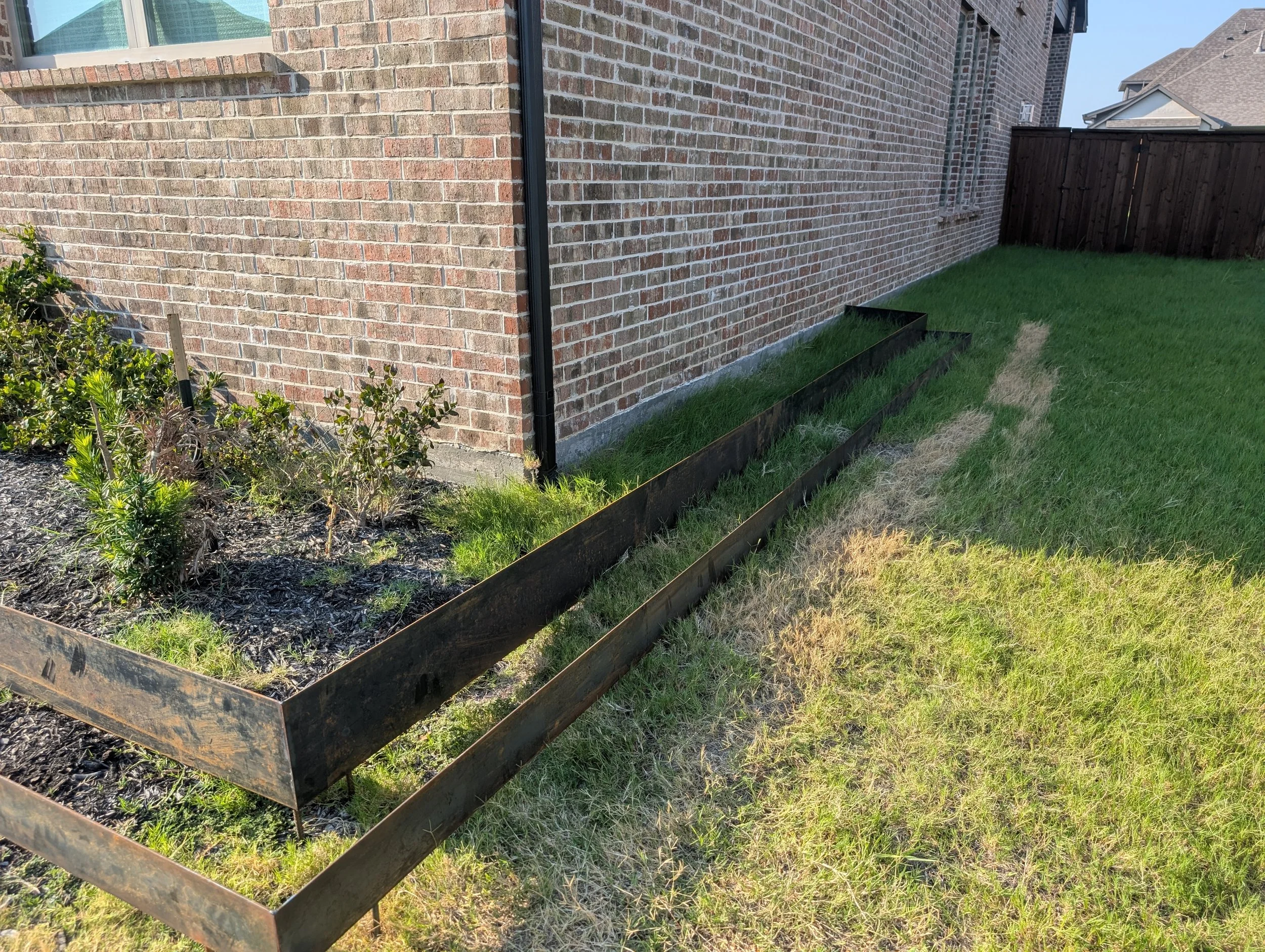 Custom steel landscape planter with decorative stone installed in Prosper, TX