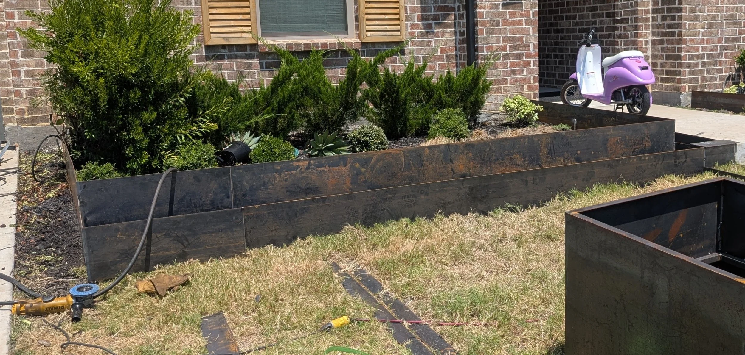 Large custom welded steel planter installed beside a brick column in Prosper, TX