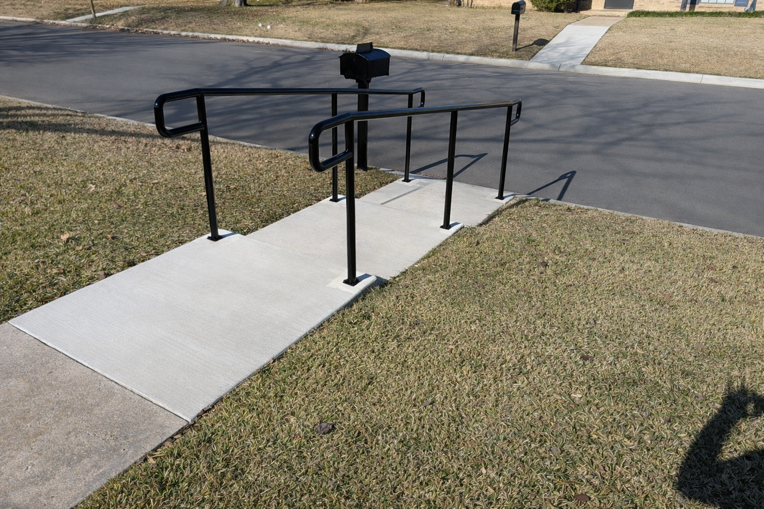 Custom black steel handrails fabricated and installed along a residential walkway in North Texas