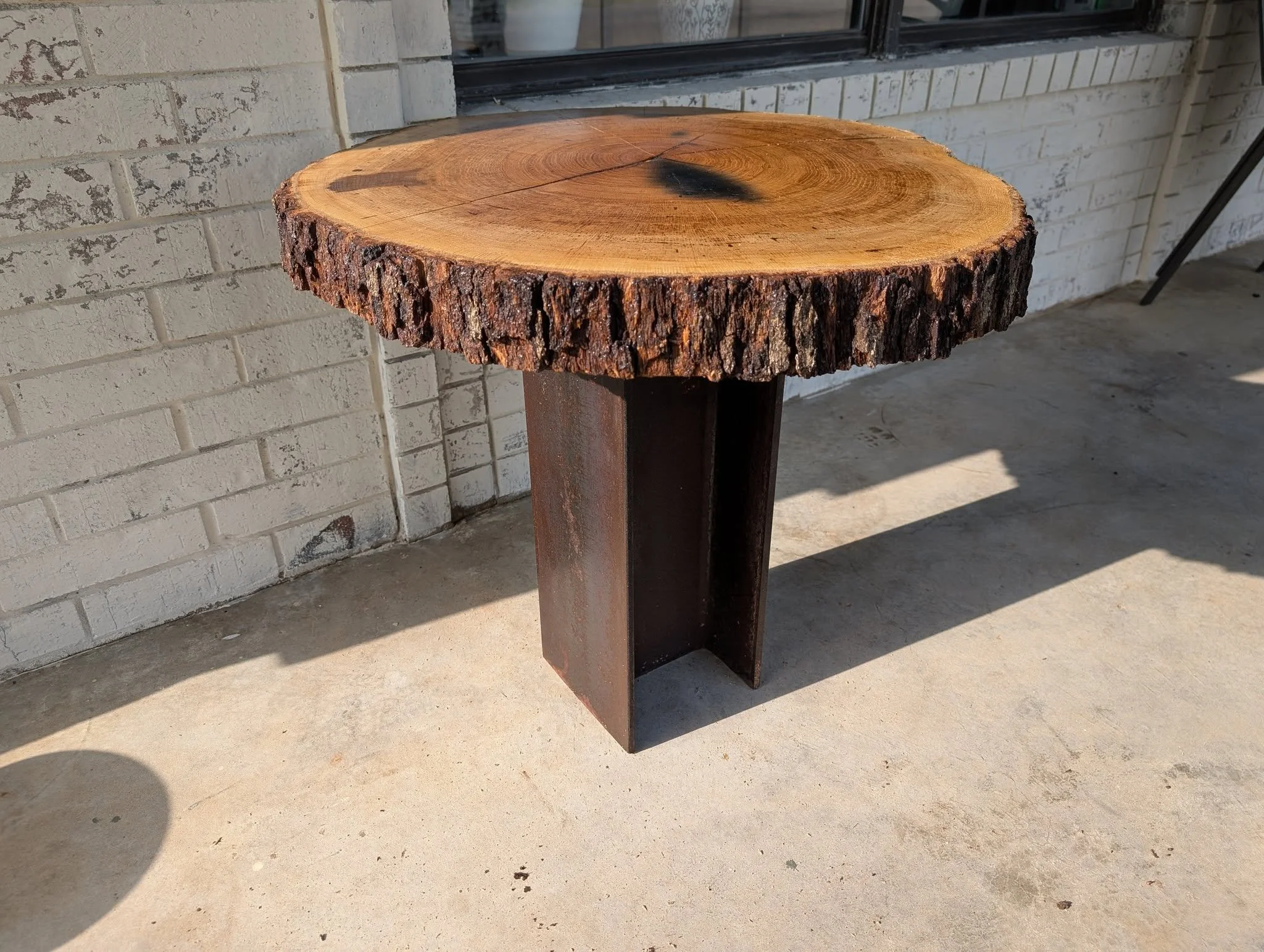 Custom live edge wood table with welded steel pedestal base fabricated by JH Tig Works LLC in North Texas