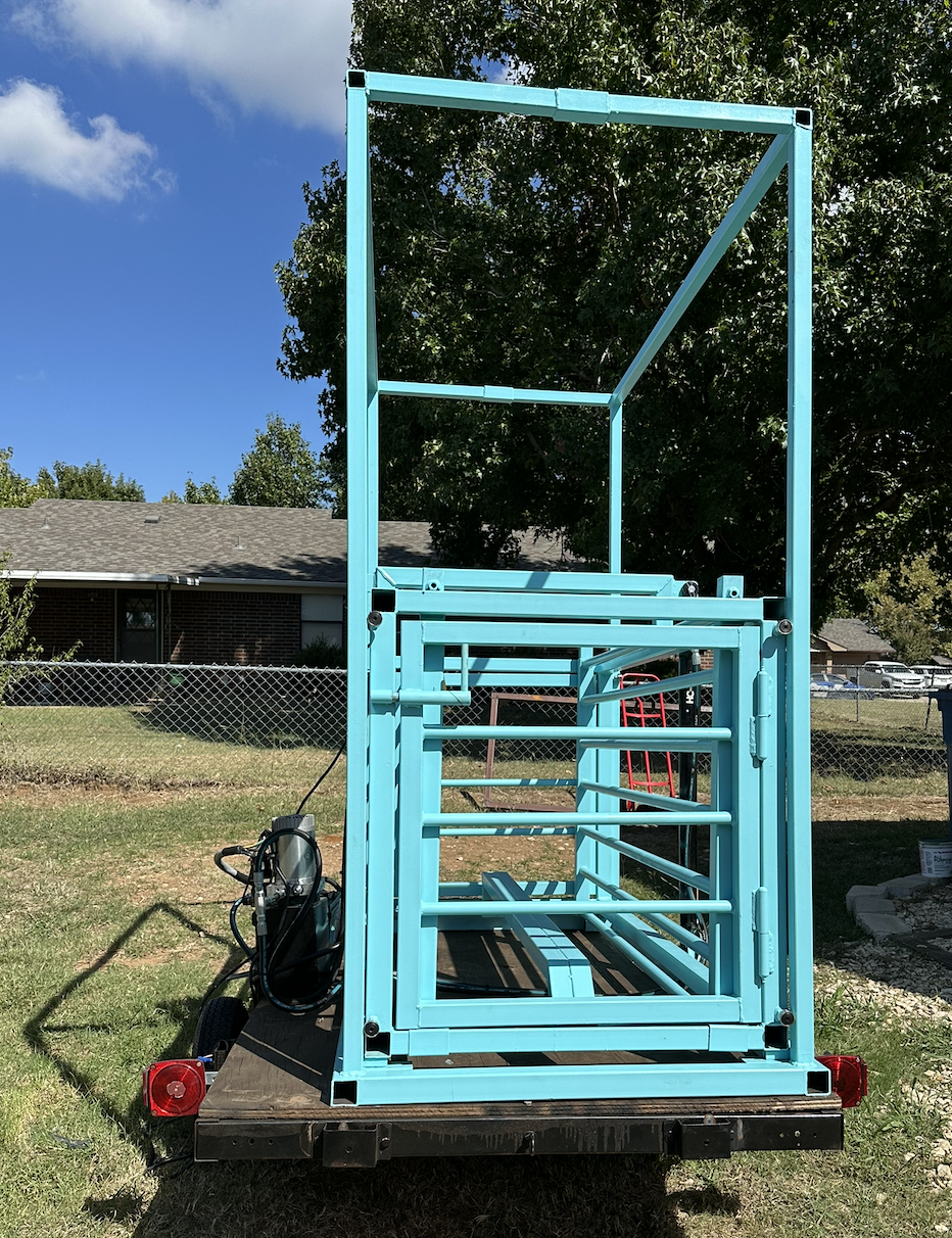 Rear view of custom hydraulic pig chute showing welded steel frame and livestock handling gate system.