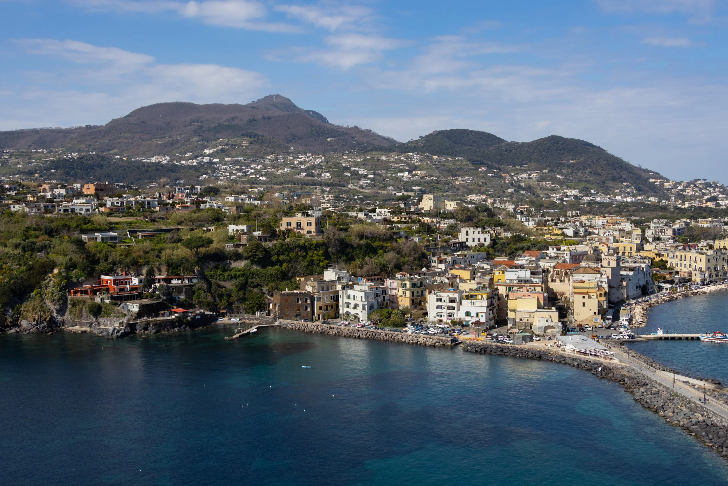 Ischia, Italy | A coastal view of Ischia, where colorful buildings stretch along the blue waters of the island. 