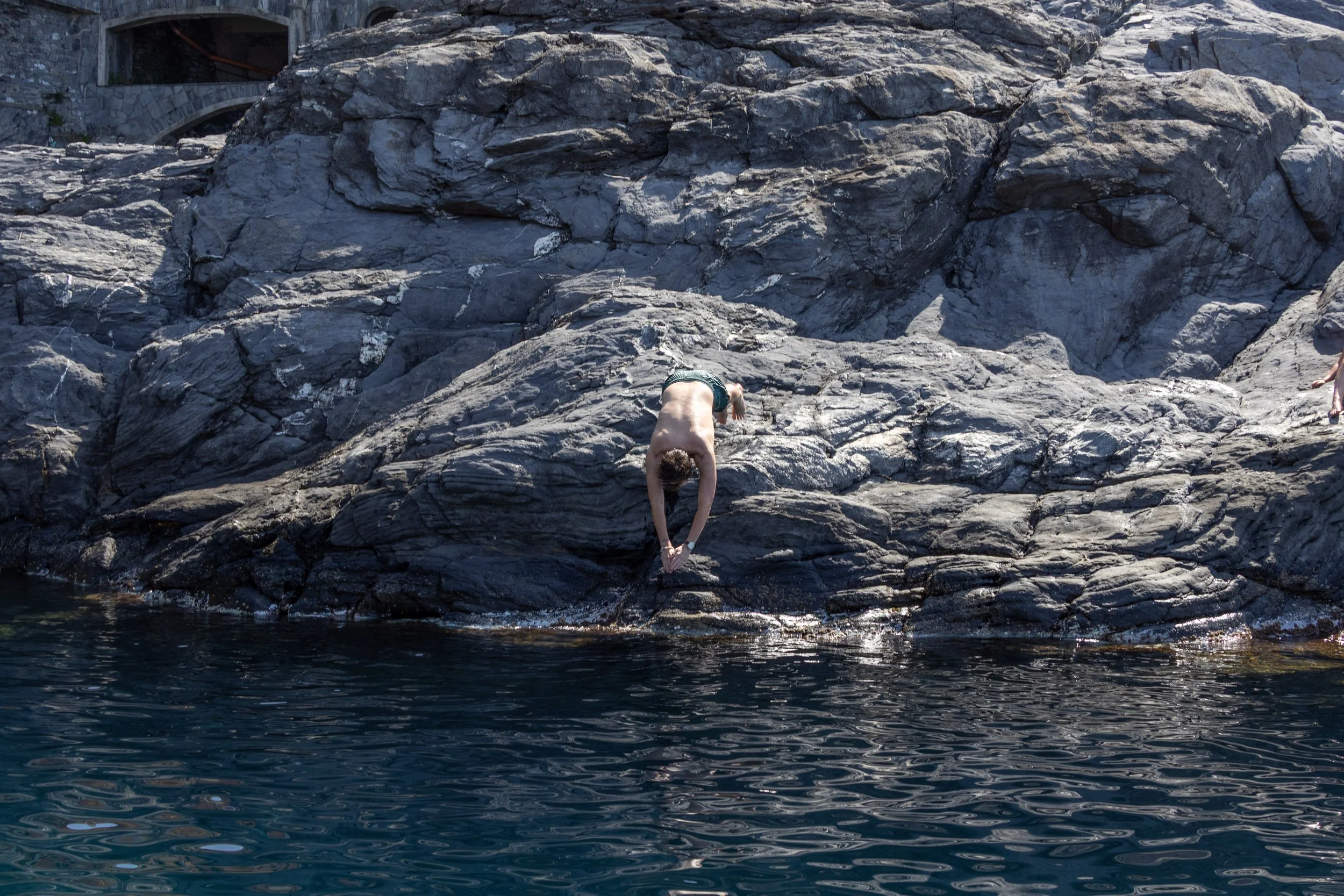 Cinque Terre, Italy | A young guy prepares to dive from the rocky coastline of Cinque Terre.