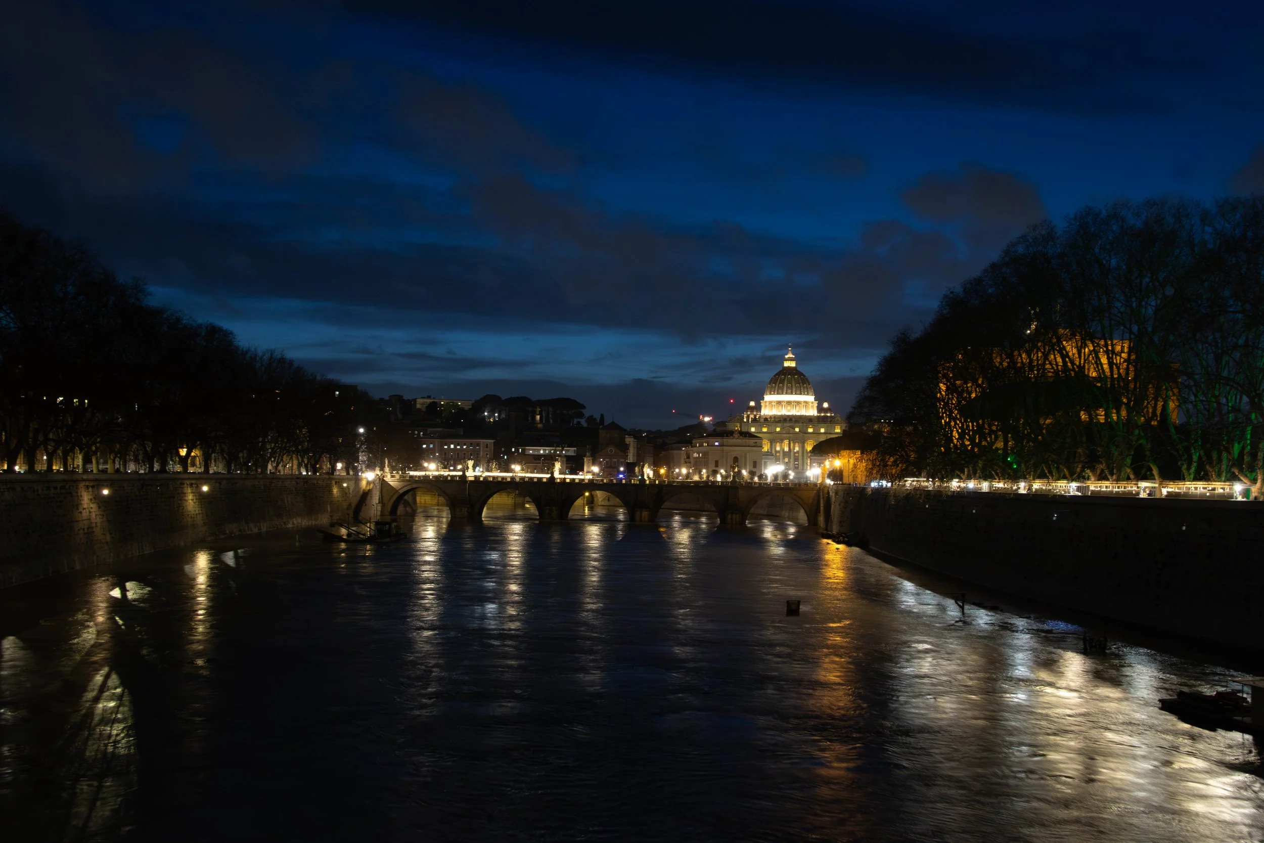 Rome, Italy | Evening view of the Tiber River with St. Peter's Basilica in the distance. 