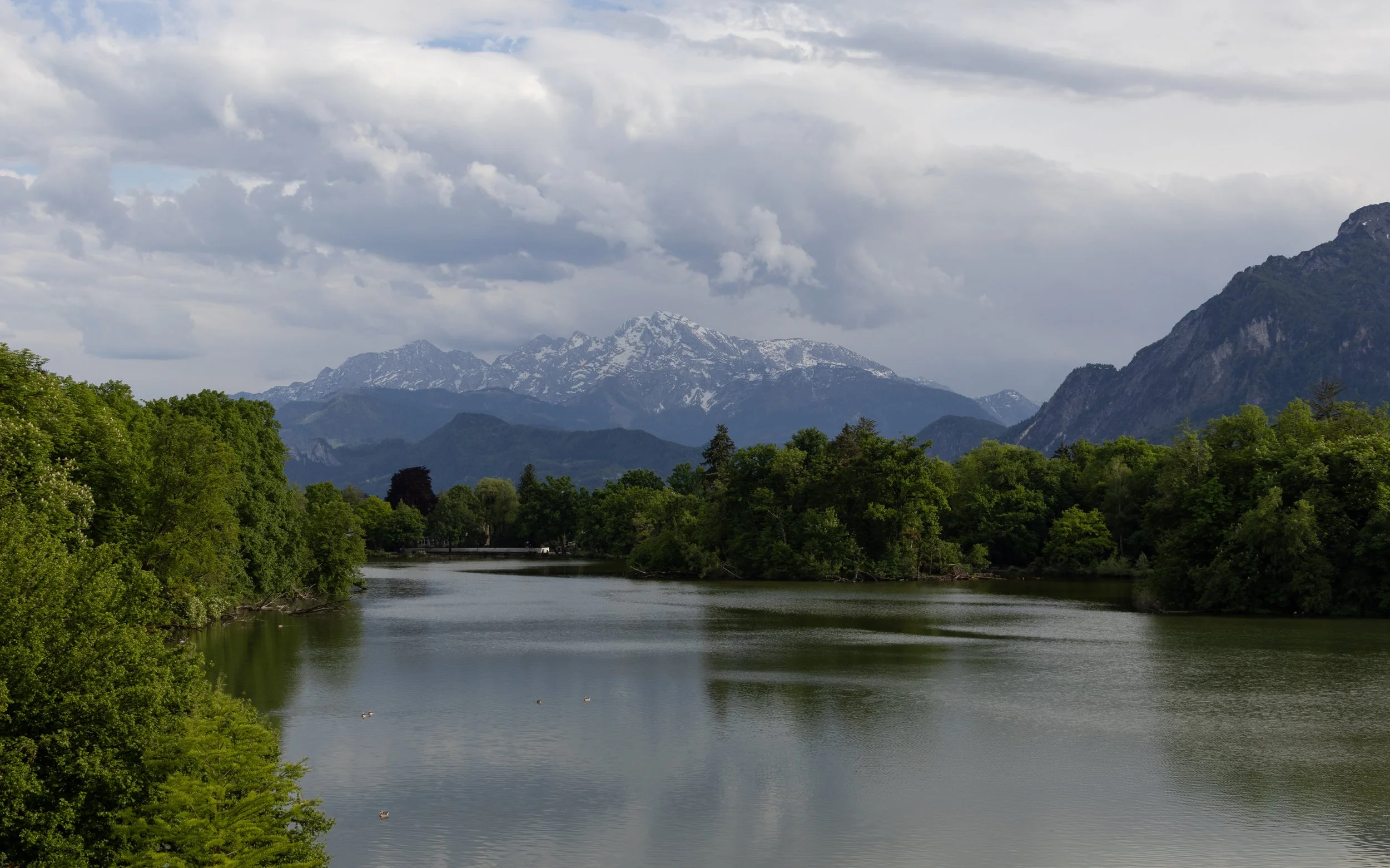 Salzburg, Austria | Snow-covered peaks rising beyond the water and the surrounding landscape. 