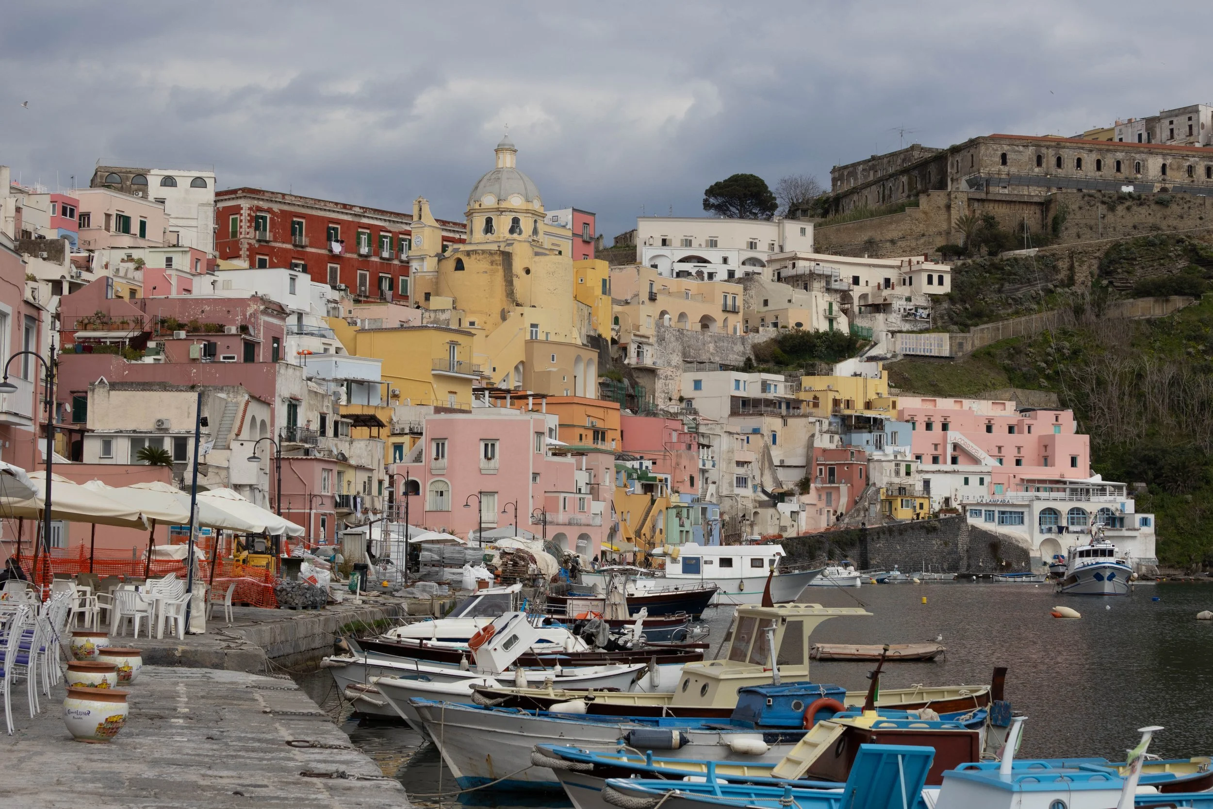 Procida, Italy | Colorful buildings rise above the boats and the waterfront of Procida. 