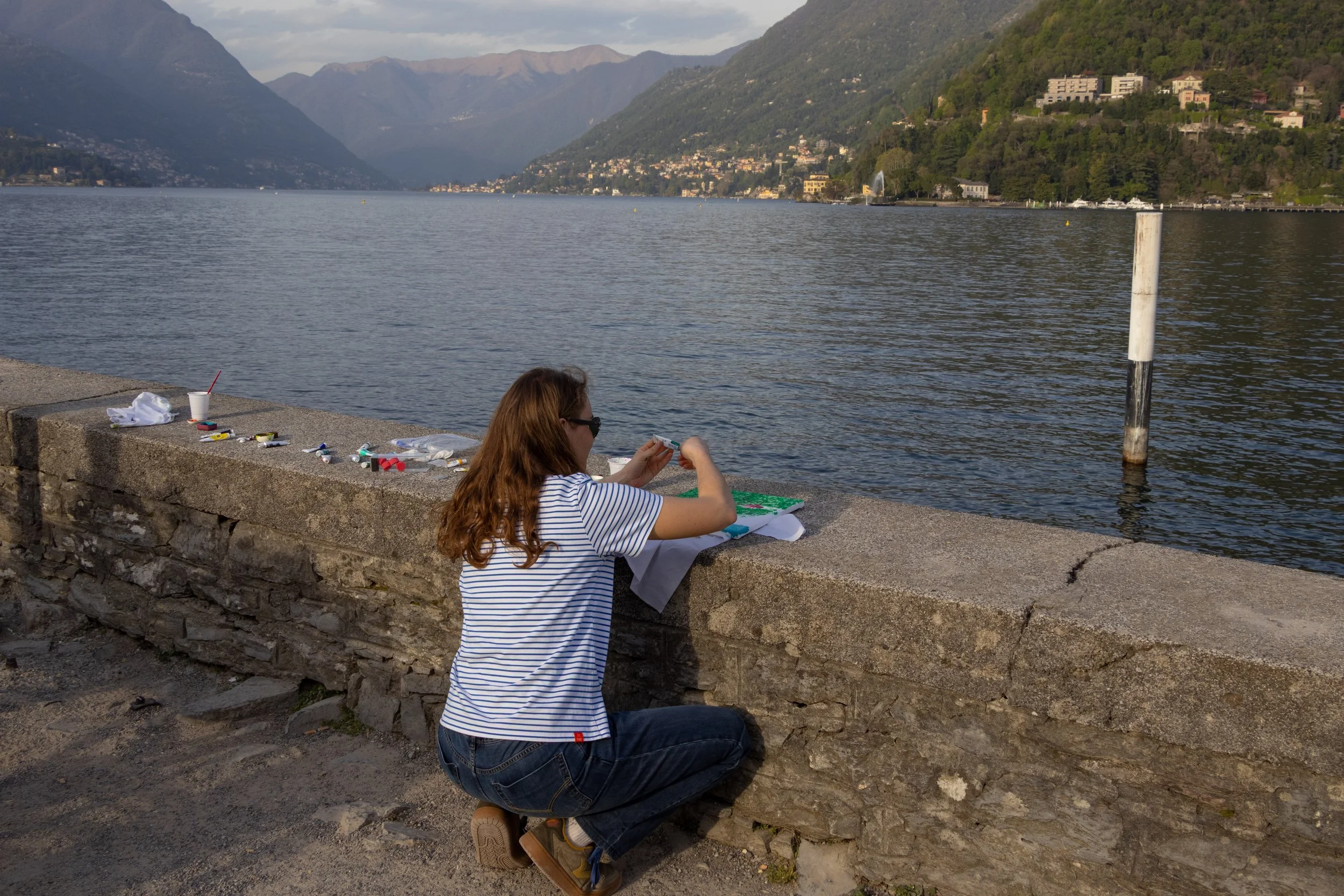 Lake Como, Italy | An artist works along the shore of Lake Como, surrounded by the lake and mountain landscape. 