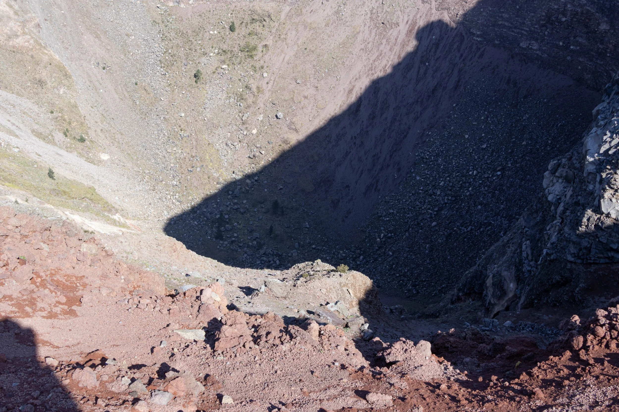 Naples, Italy | A view into the volcanic crater of Mount Vesuvius, revealing its steep slopes and rugged volcanic terrain. 