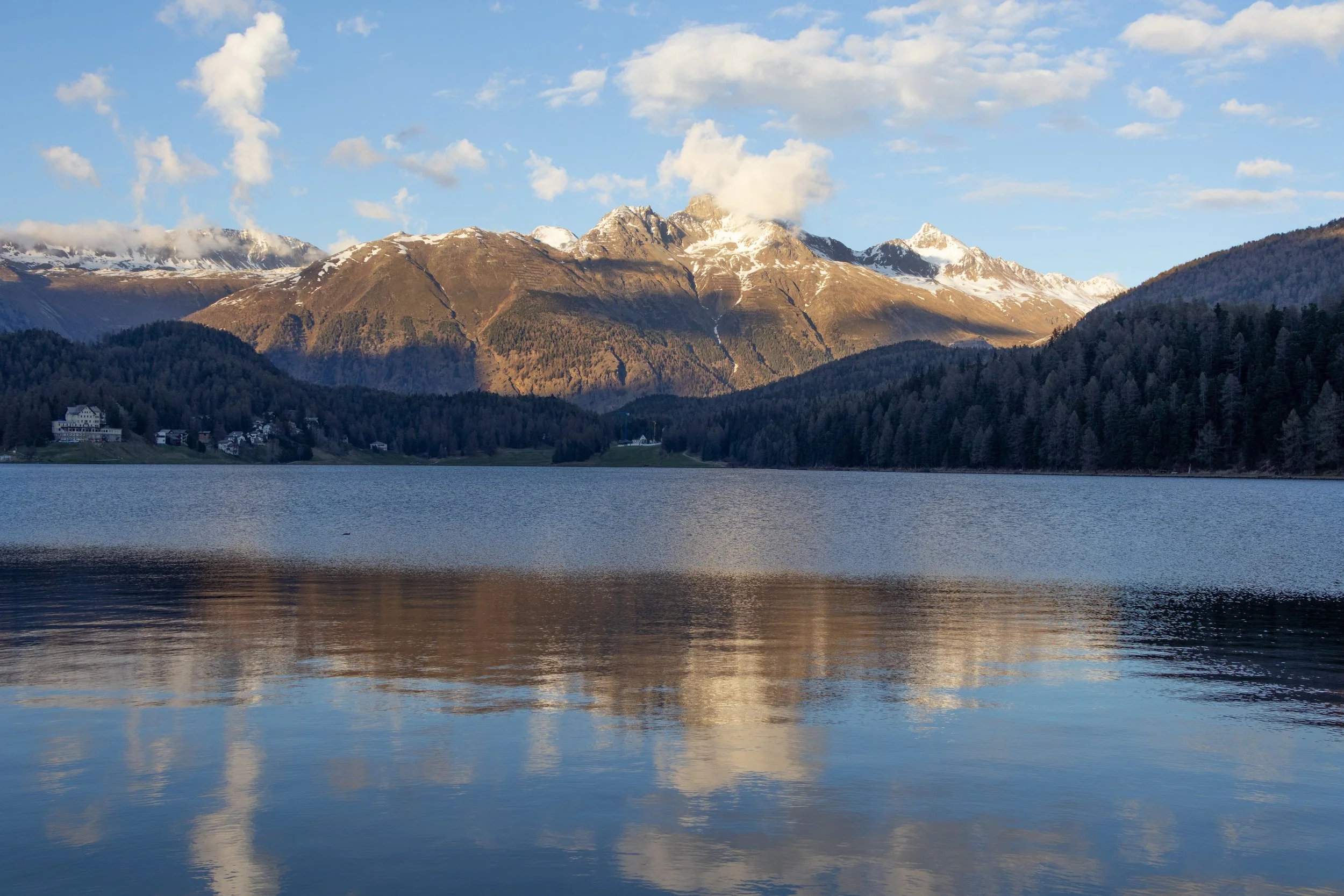 St. Moritz, Switzerland | Warm evening light across the mountains reflected in the lake.