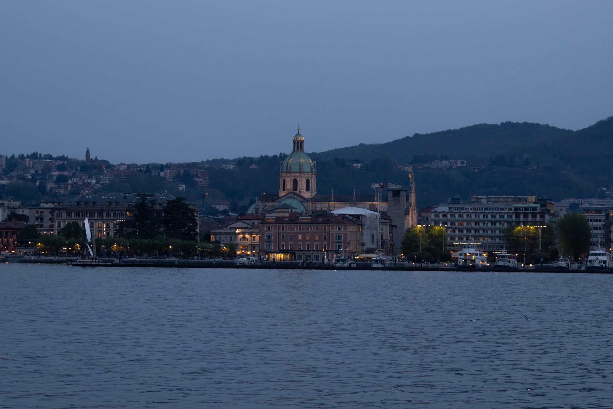 Lake Como, Italy | The city of Como begins to glow along the waterfront as evening settles over Lake Como.